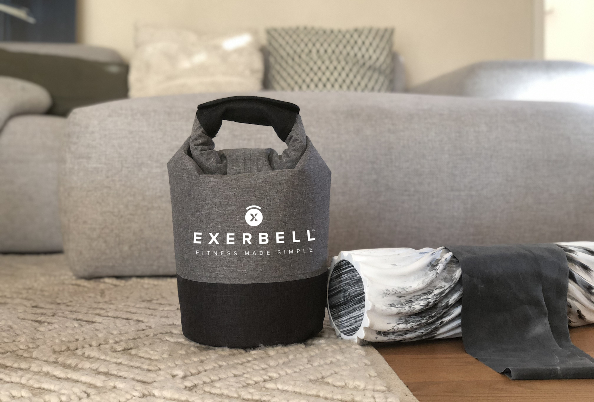 Sac Exerbell gris avec base noire, à côté d'un rouleau en mousse et d'une bande.