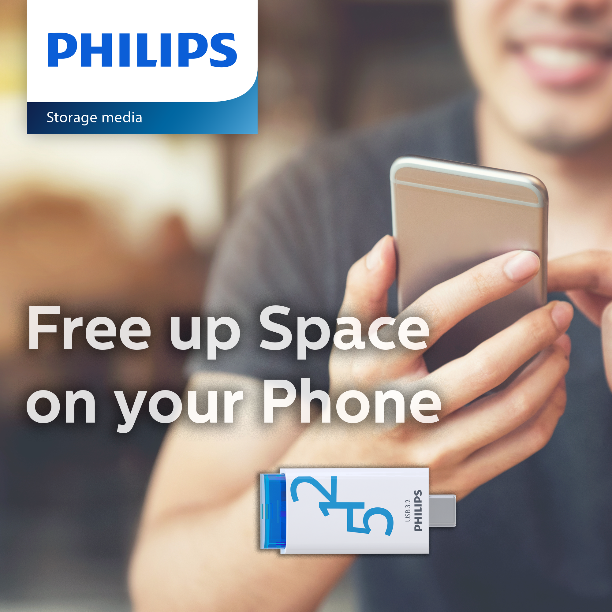 Ein Mann benutzt ein Smartphone, daneben ein Philips USB-Speicherstick.