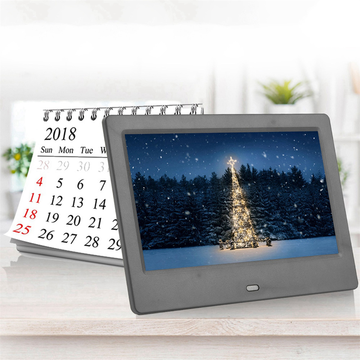 Ein Kalender von 2018 und ein digitaler Bilderrahmen mit einem Weihnachtsbaum im Schnee.