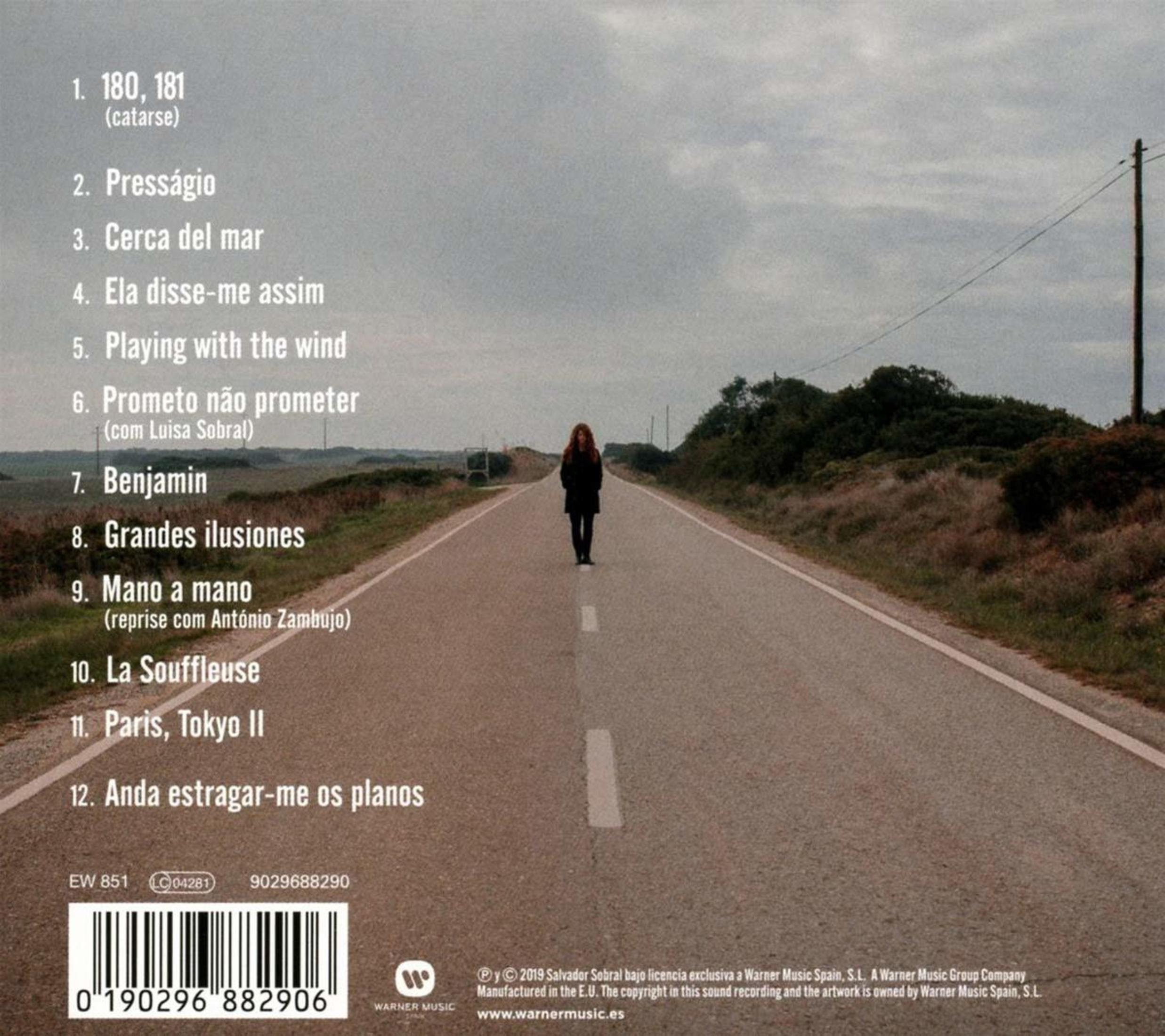 Una donna si trova su una strada alberata. Elenco tracce in primo piano.