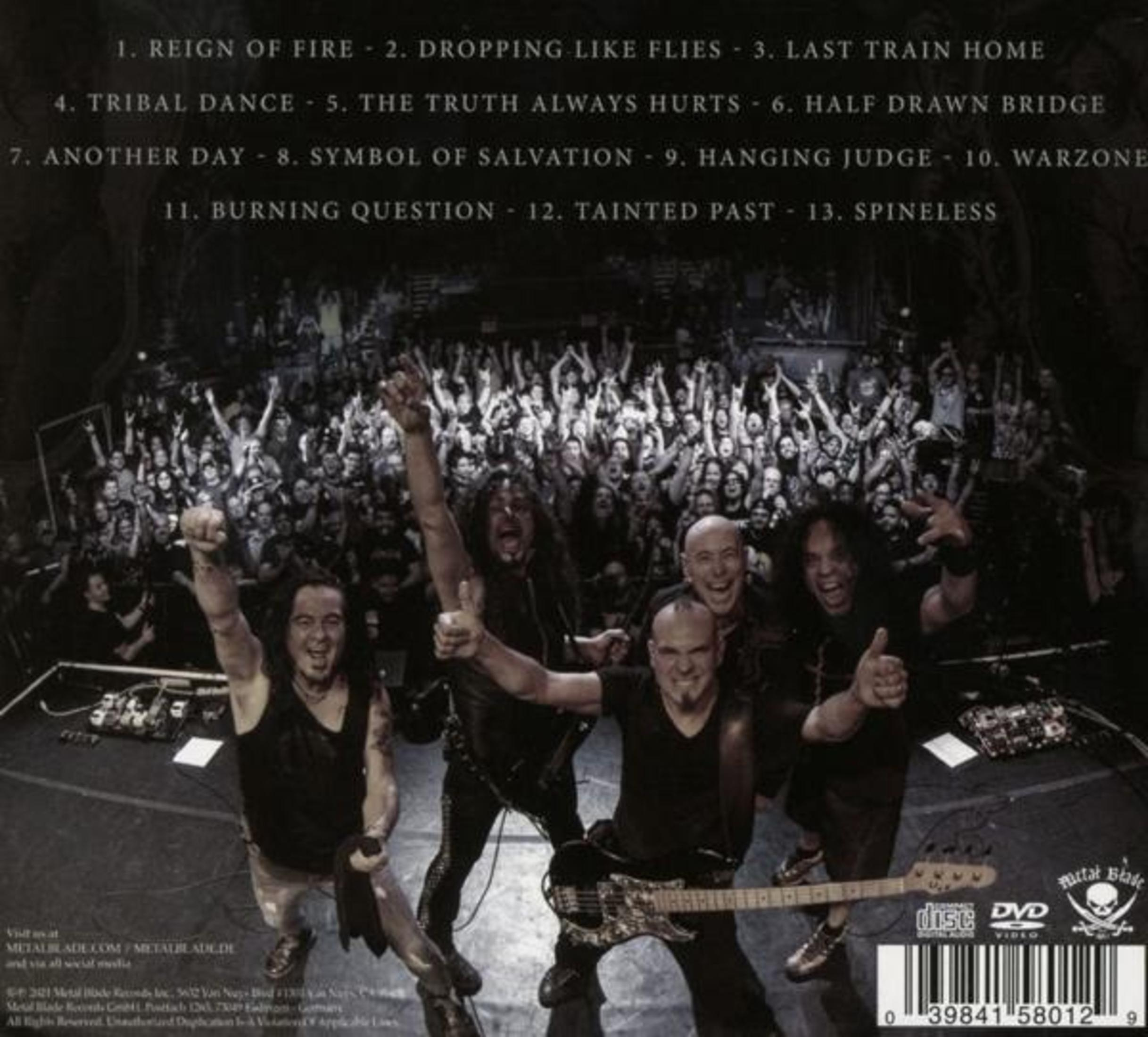 Band suona davanti a folla festante, lista canzoni visibile.
