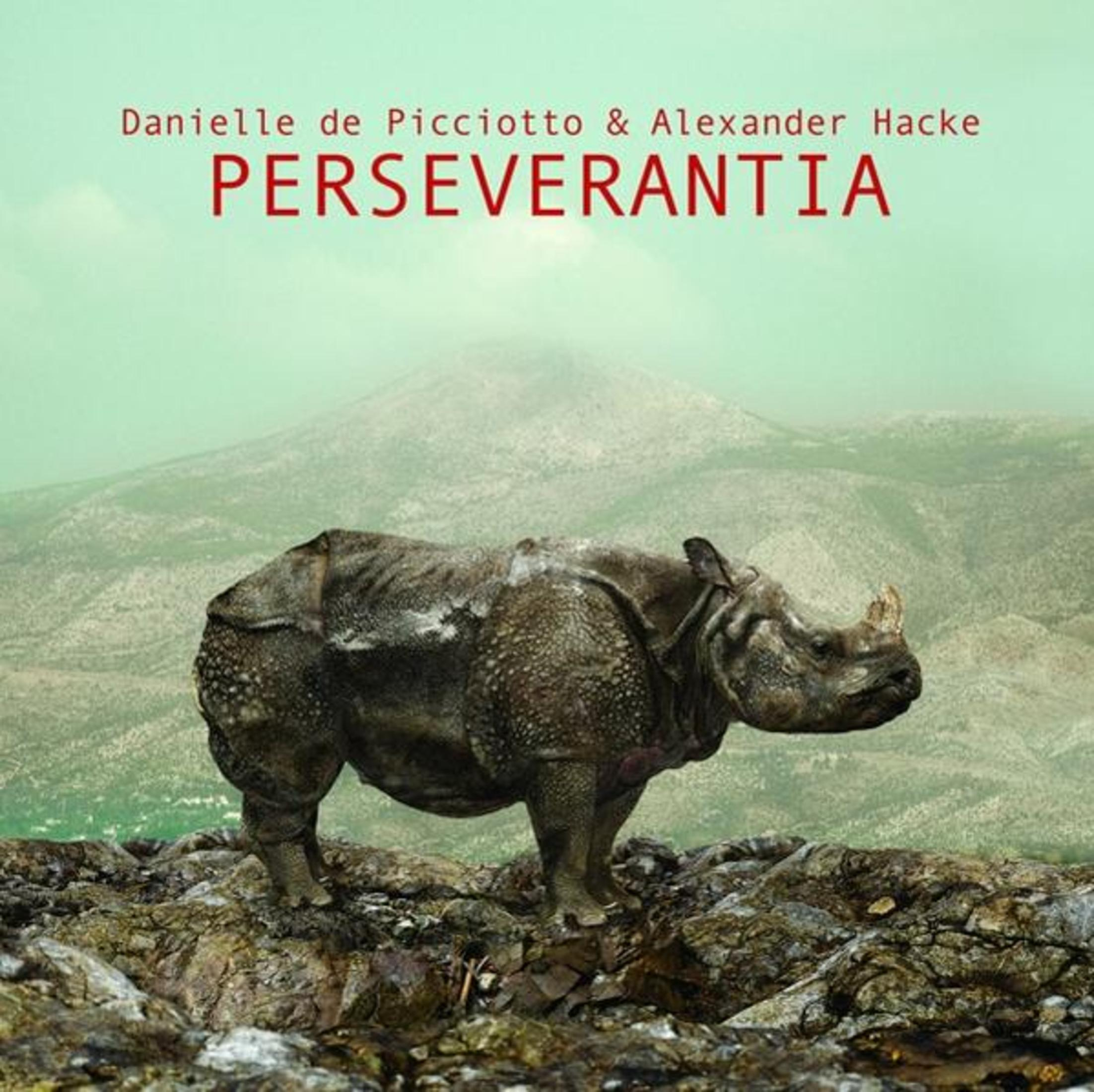 Un rinoceronte si erge su terreno roccioso davanti a un paesaggio montuoso.