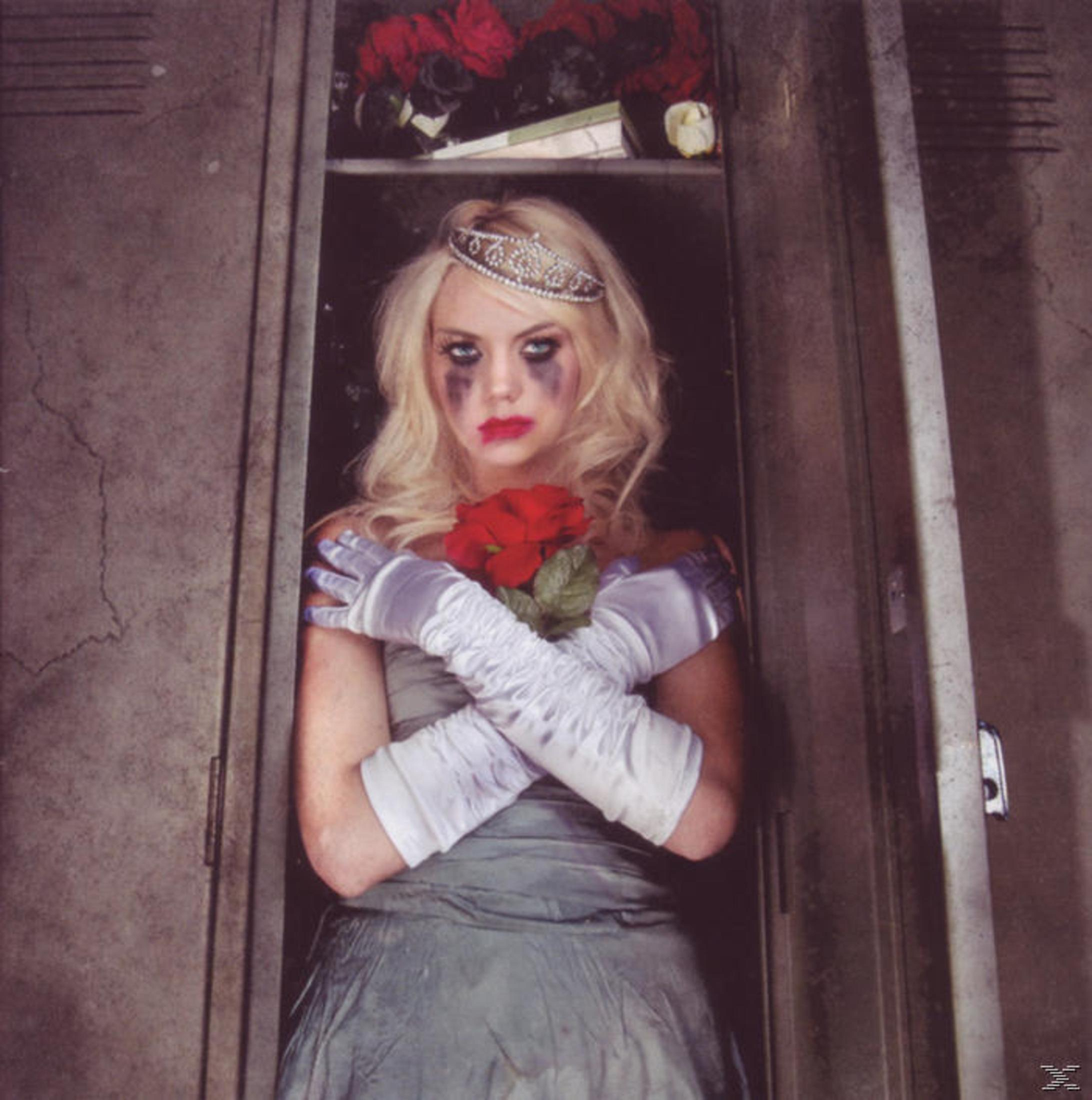 Una donna con tiara e trucco sbavato tiene una rosa rossa in un armadietto.