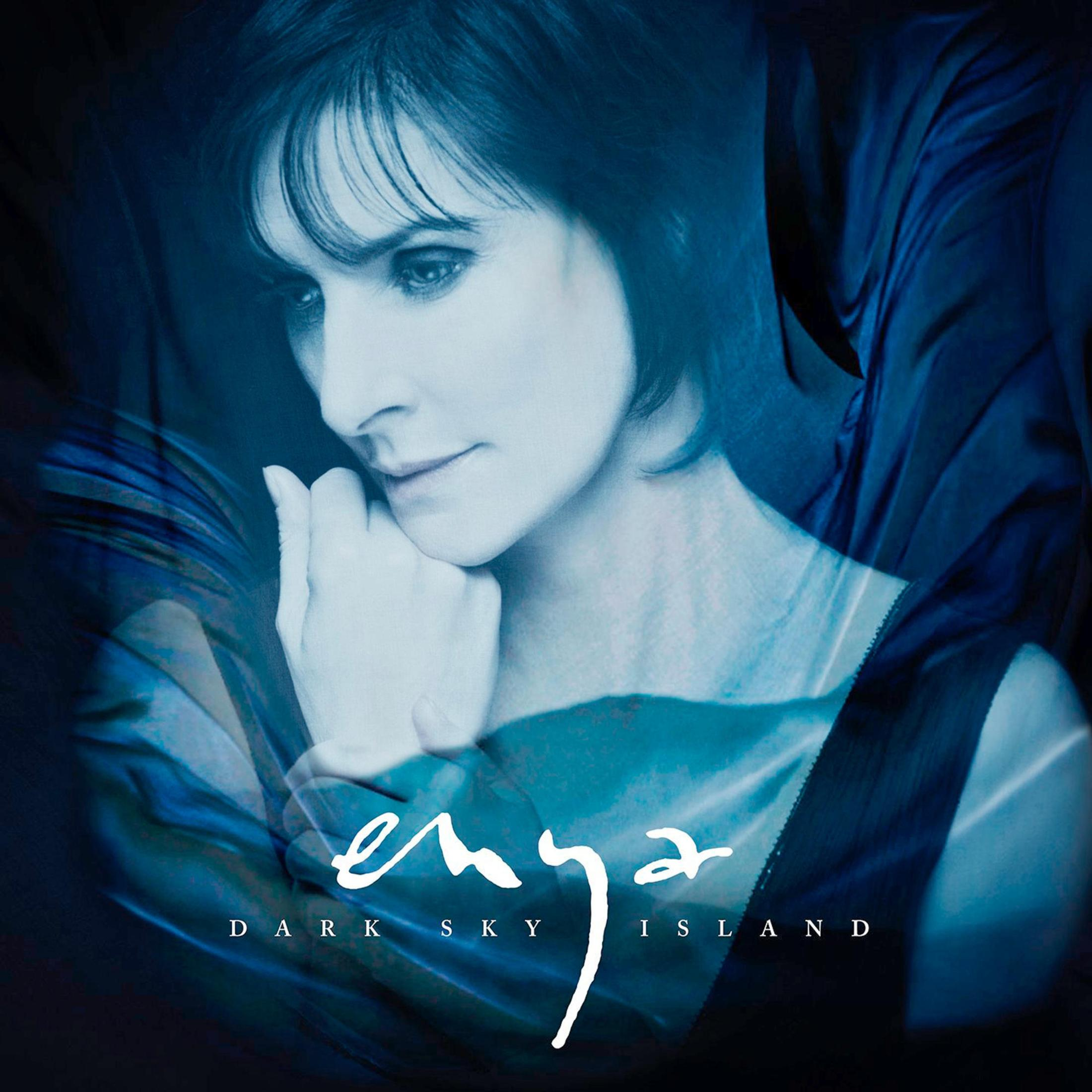 Enya guarda a sinistra, mano sul mento, con tessuto blu scuro che turbina.