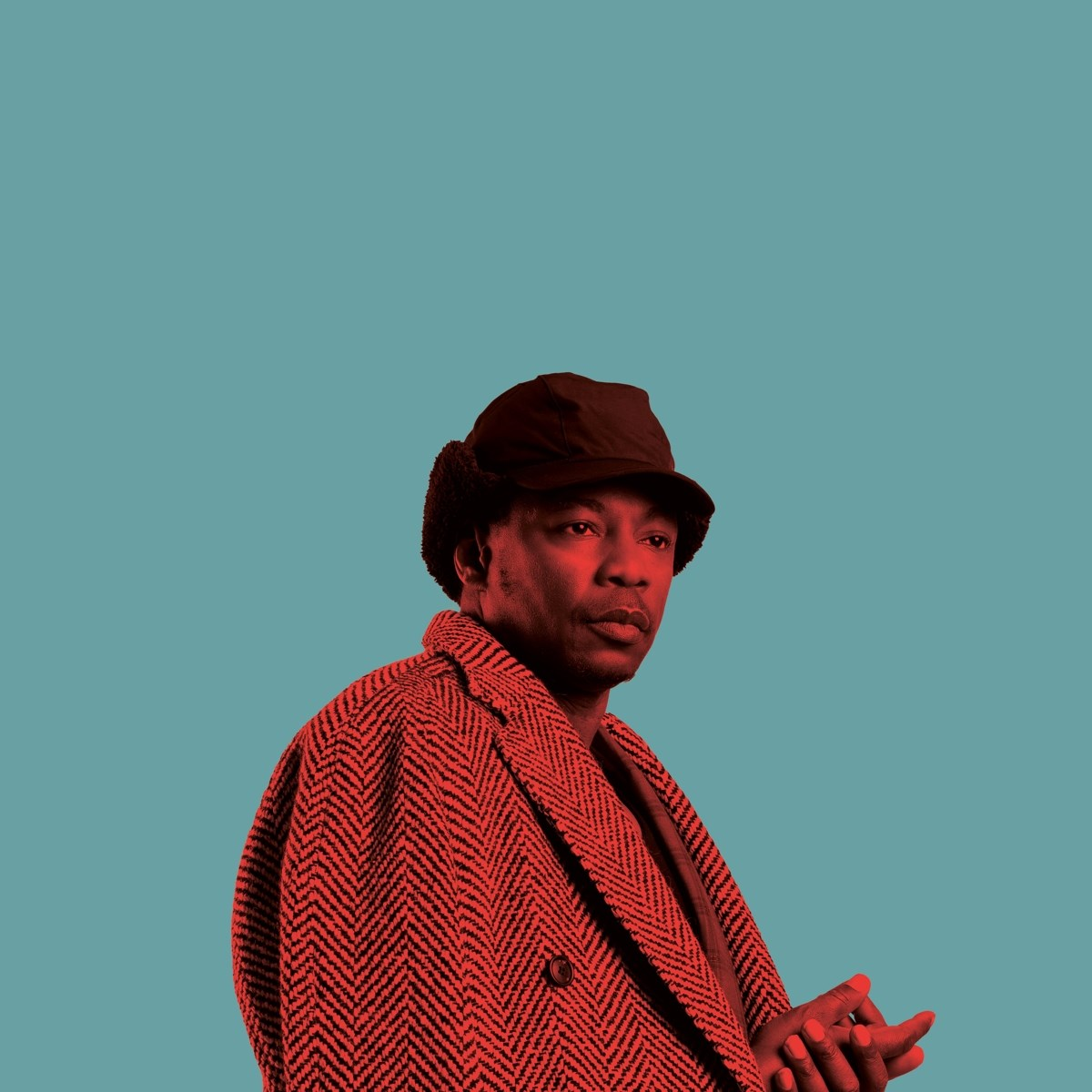 Un uomo in cappotto rosso spigato e cappello su sfondo blu.