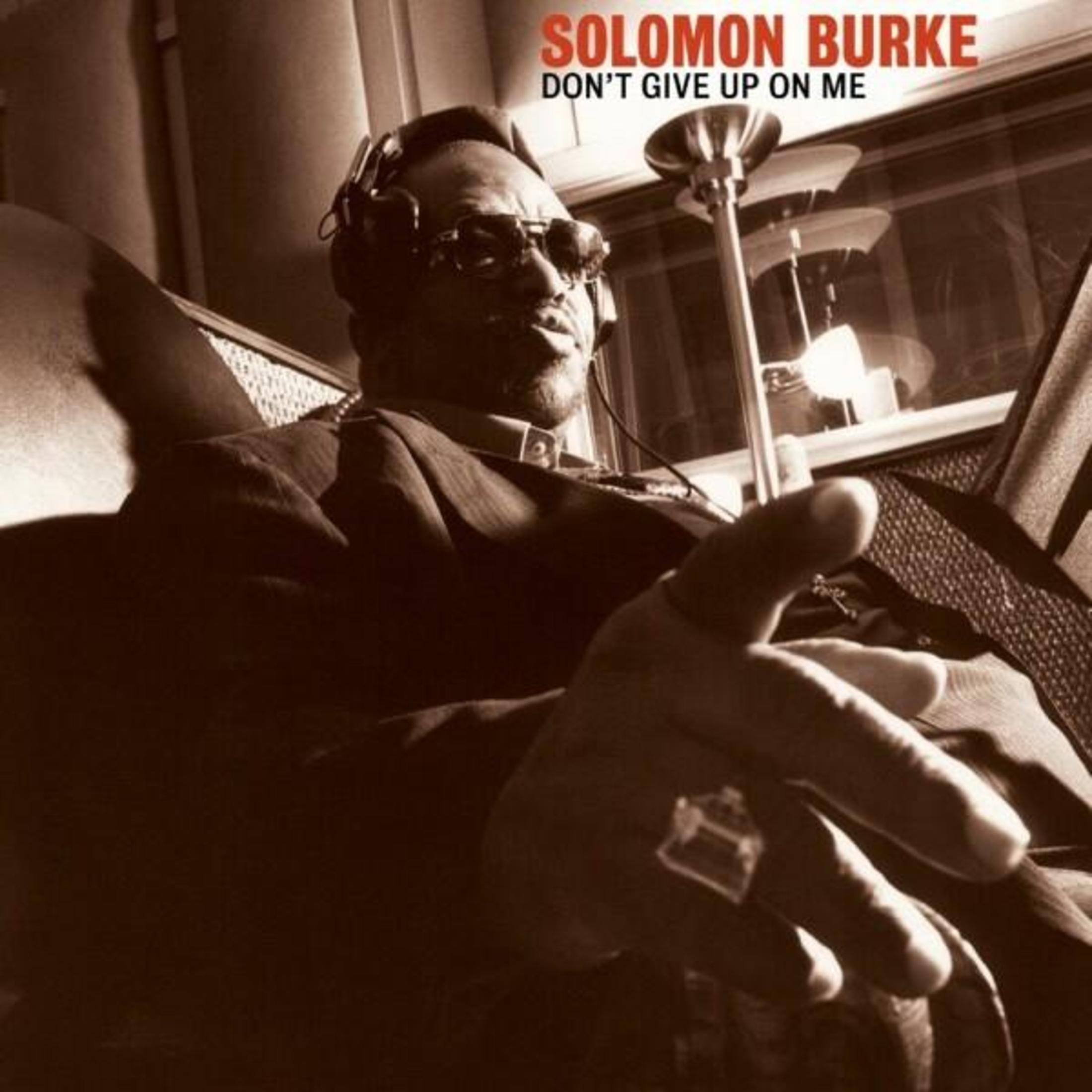 Solomon Burke con cuffie e occhiali siede su una poltrona, protendendosi in avanti.