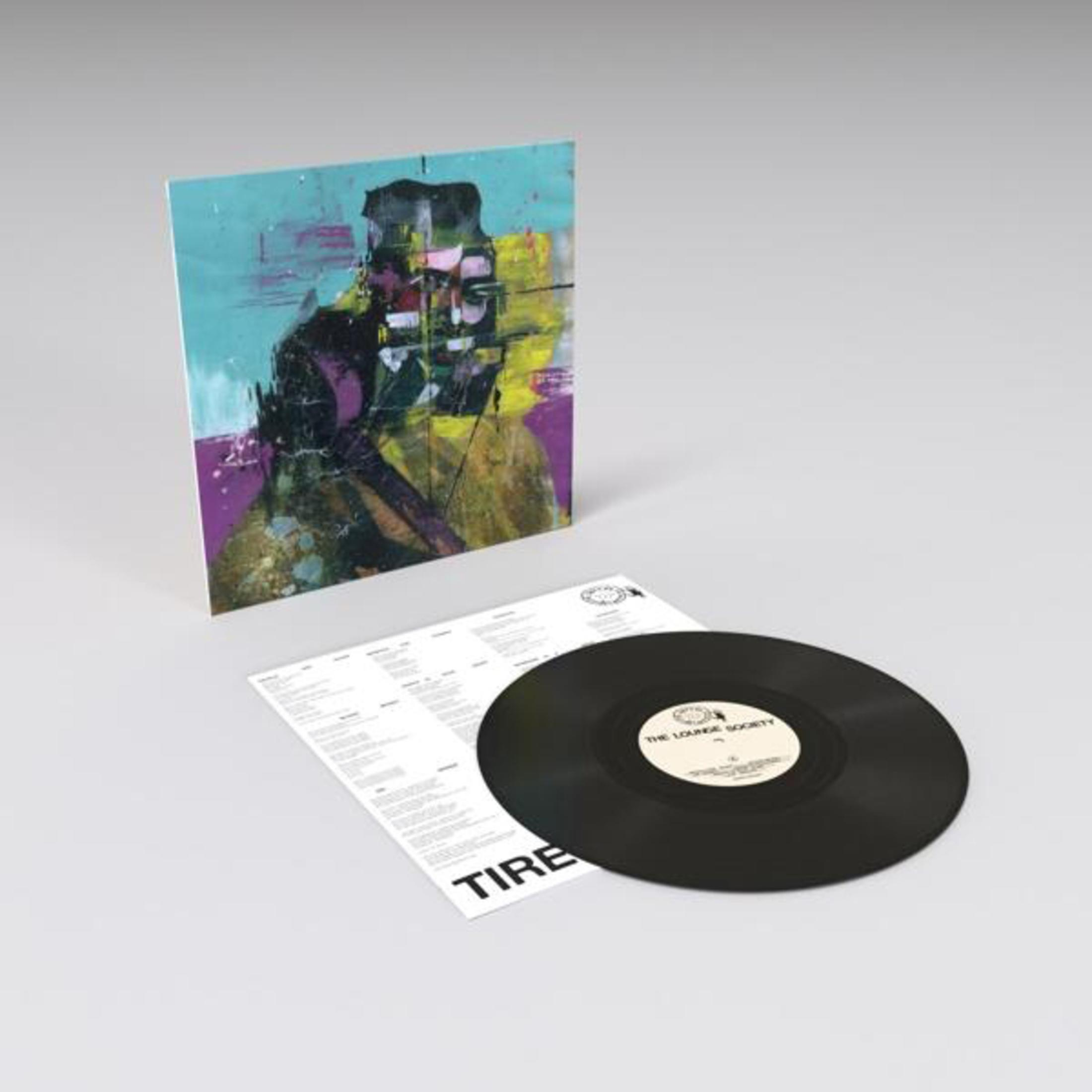 Disco in vinile con copertina astratta e inserto stampato su sfondo grigio.
