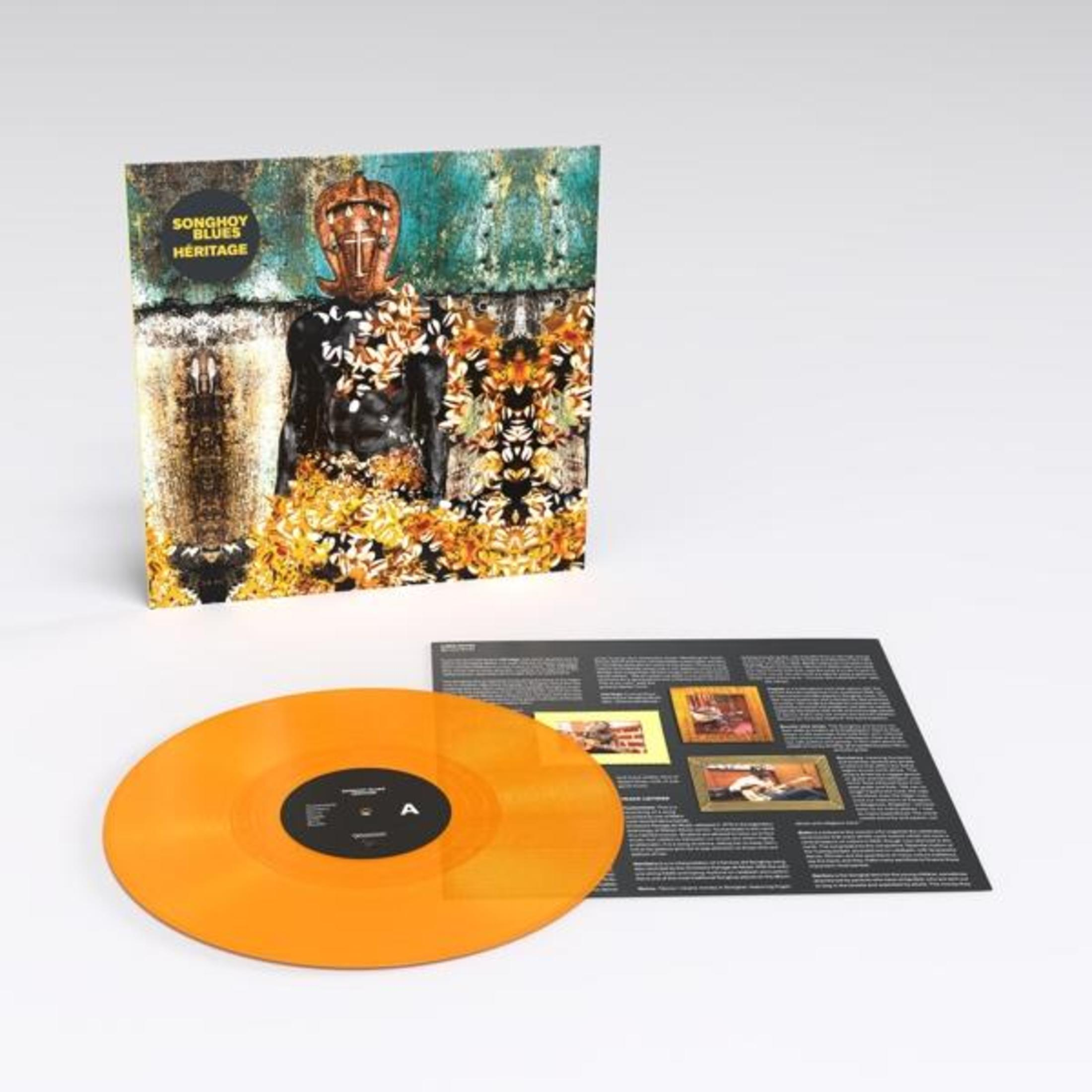 Disco in vinile arancione accanto alla copertina dell'album con motivo a maschera e testo.