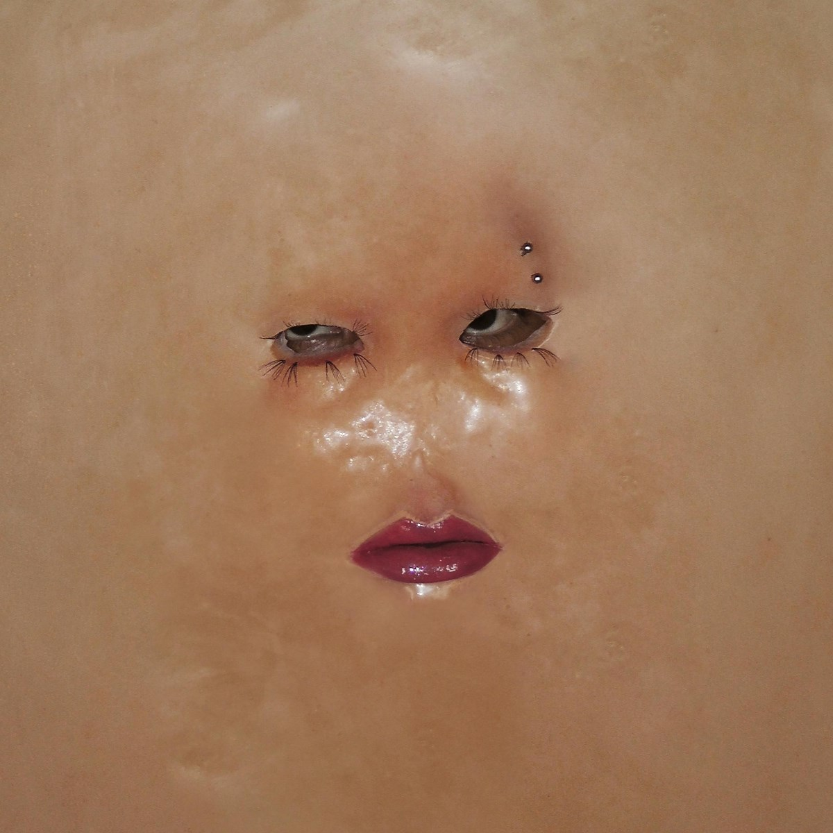 Primo piano di un viso con piercing sopra l'occhio sinistro e rossetto lucido.
