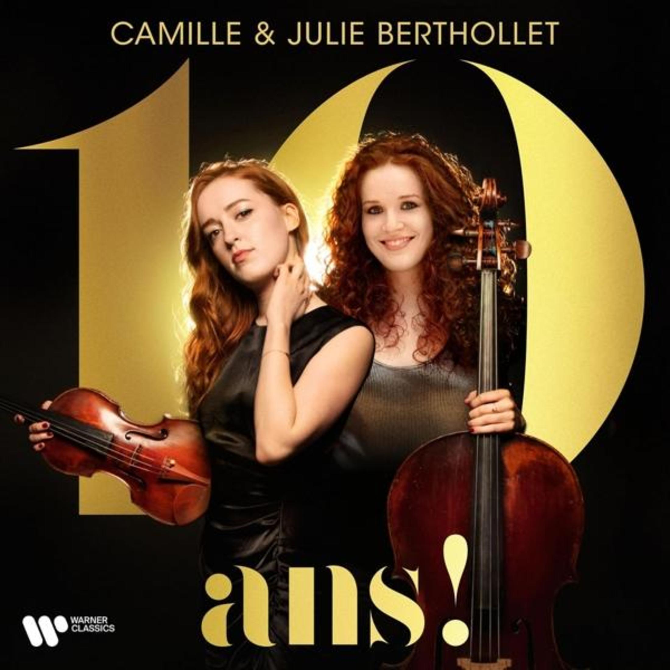 Due donne dai capelli rossi posano con violino e violoncello davanti a un '10' dorato.