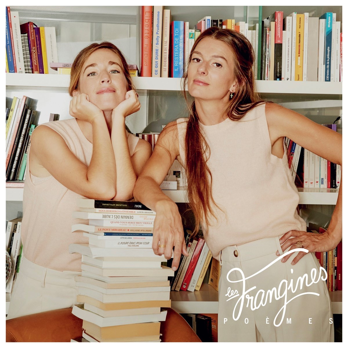 Due donne davanti a una libreria, una appoggiata sui libri.