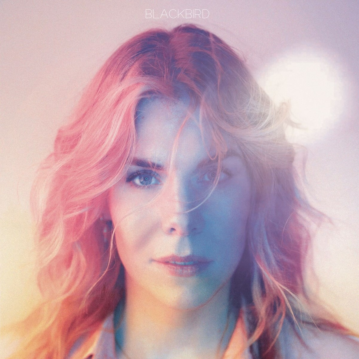 Portret van vrouw met roze haar, gezicht verlicht door blauw en roze licht.