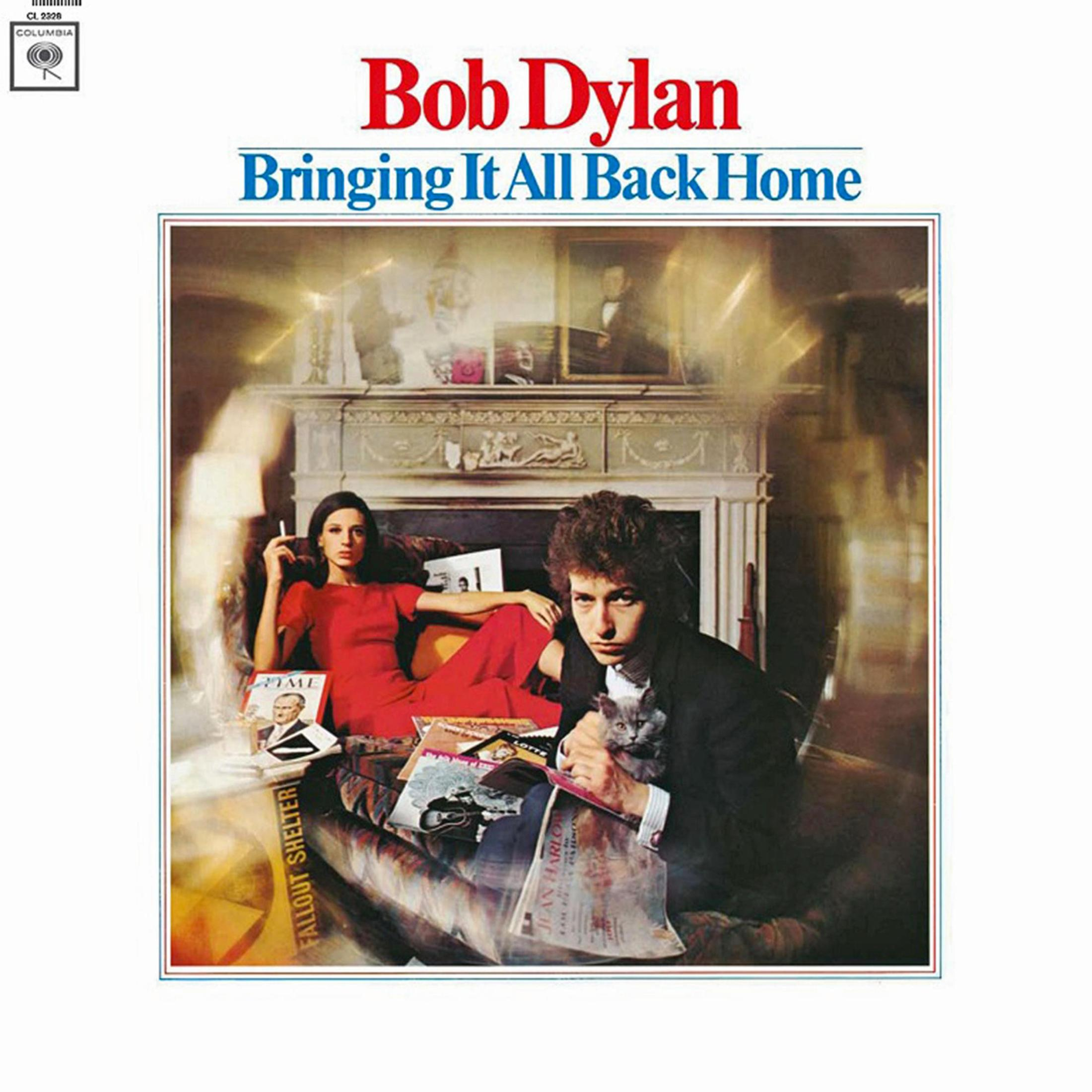 Bob Dylan con gatto e donna in abito rosso davanti a un camino.