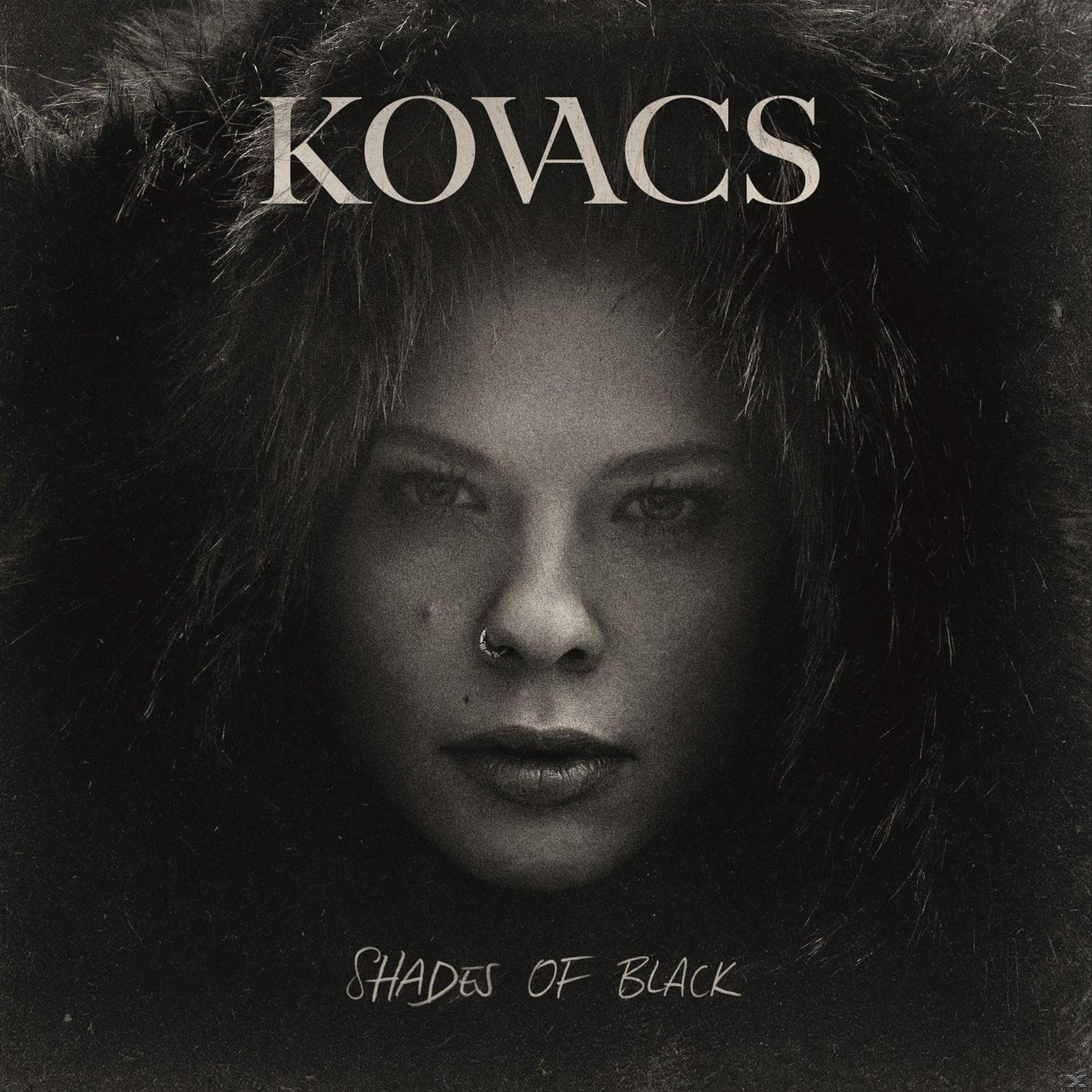 Primo piano di un viso con bordo in pelliccia, testo 'KOVACSSHADESS OF BLACK' sopra.