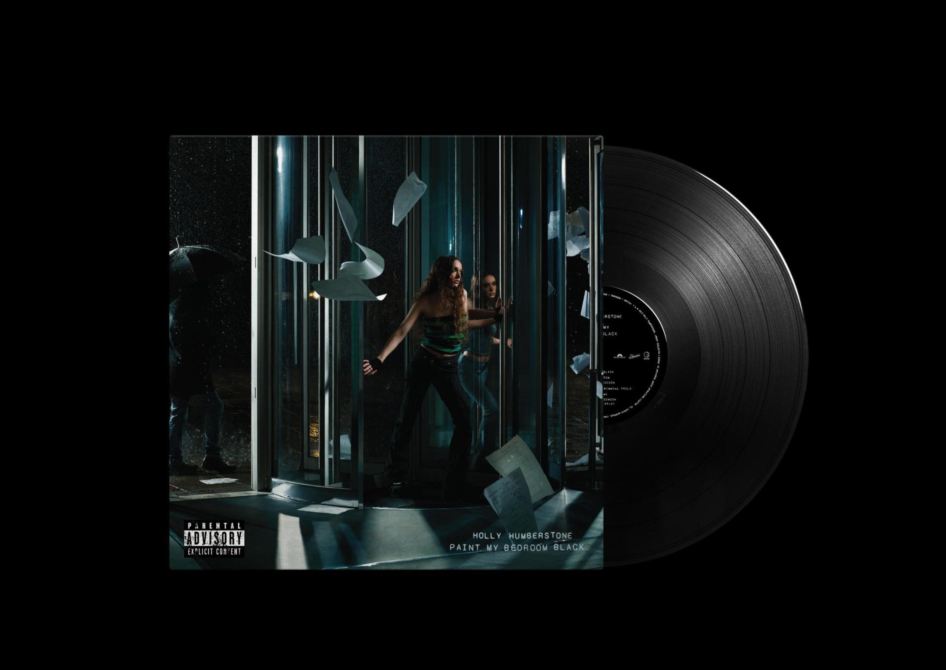 Una donna in cabina di registrazione con carta accartocciata; un disco in vinile vicino.
