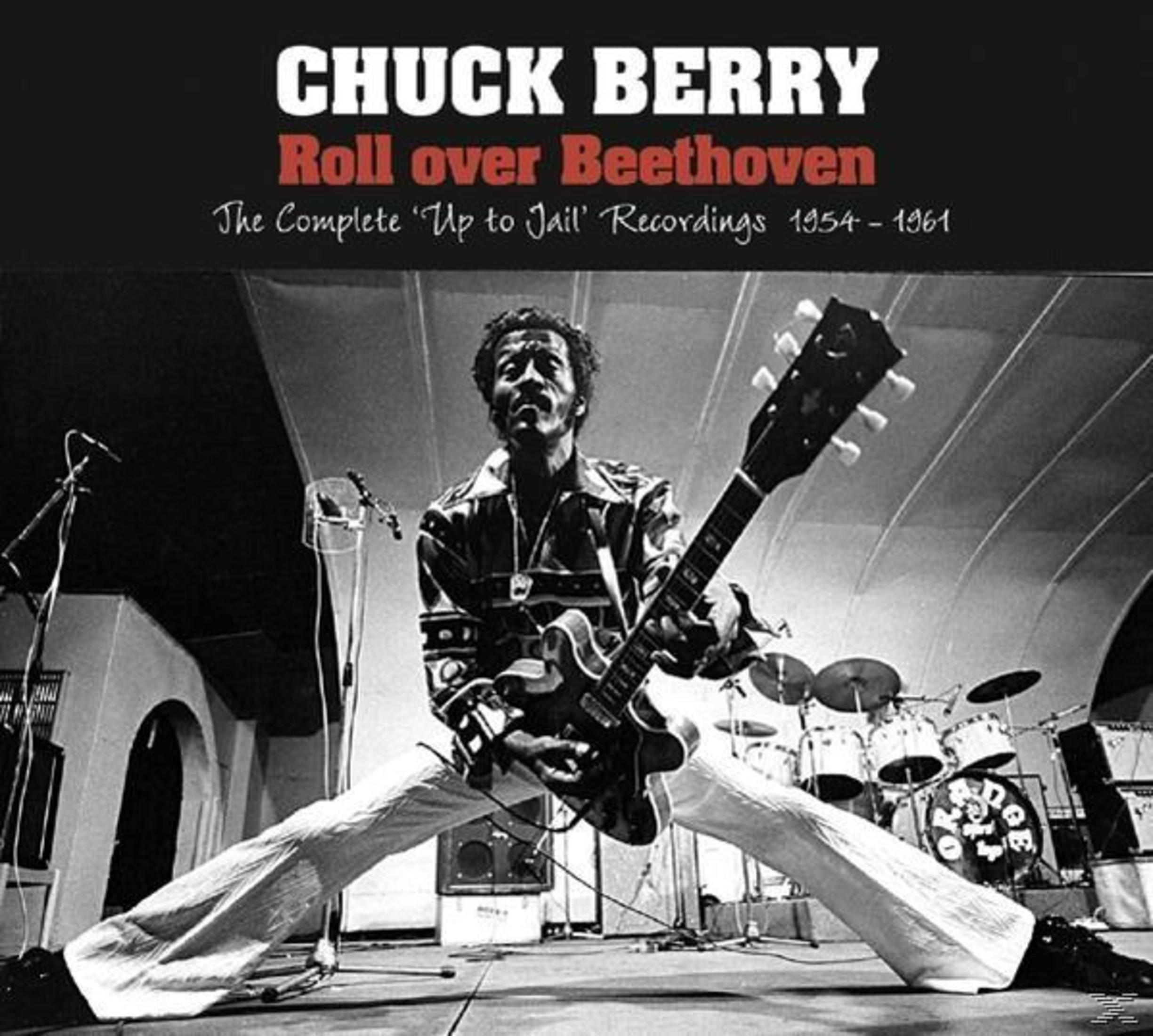Chuck Berry suona la chitarra sul palco con la batteria sullo sfondo.