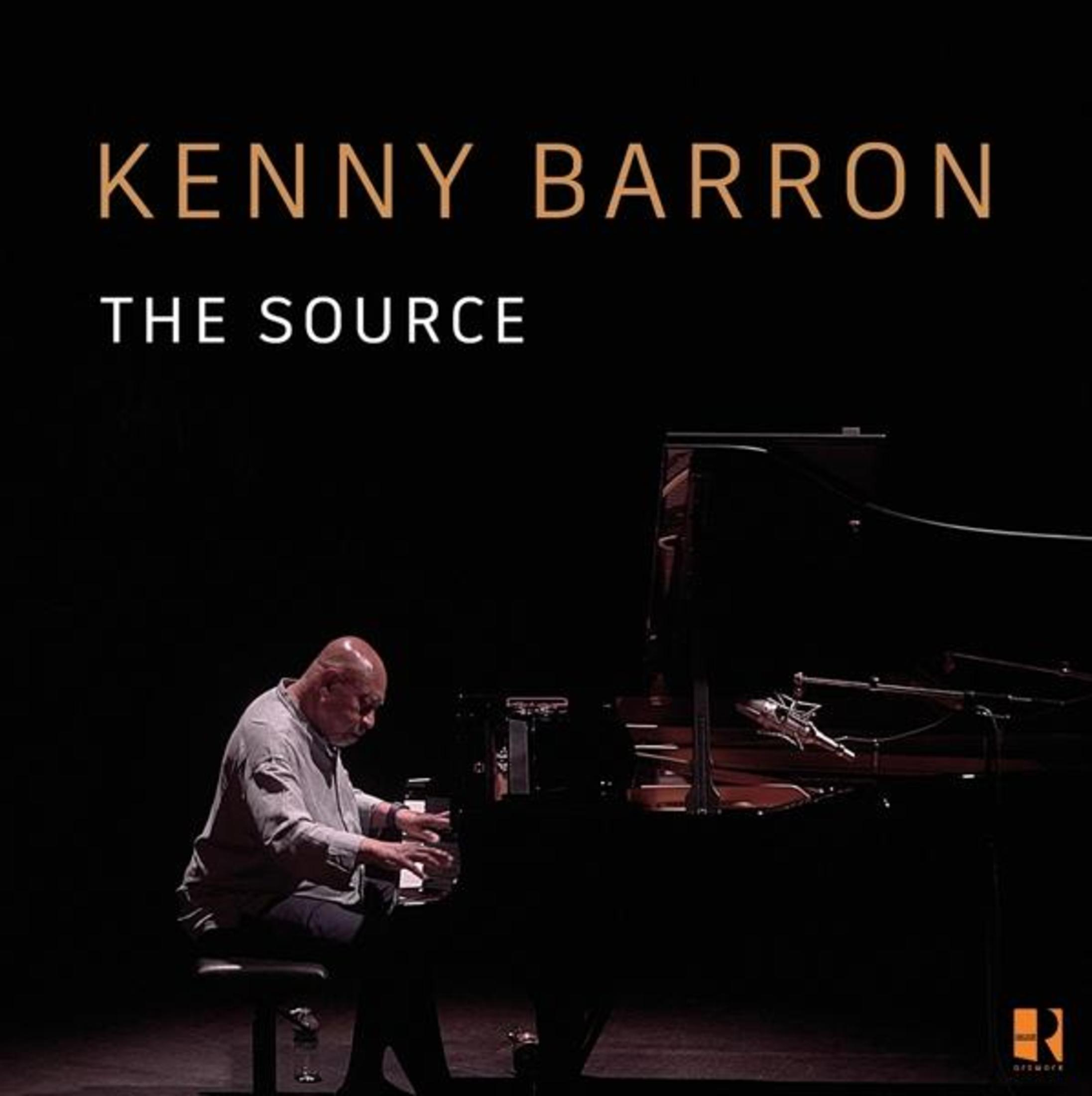Un uomo suona il pianoforte in una stanza buia. "KENNY BARRON THE SOURCE" è mostrato sopra.