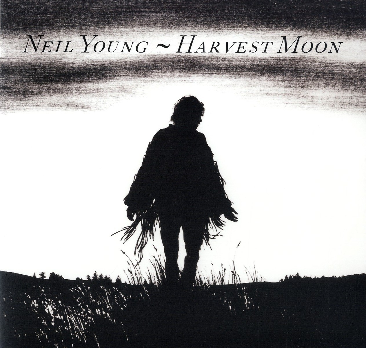 Silhouette di persona con poncho sfrangiato nell'erba. Neil Young ~ Harvest Moon.