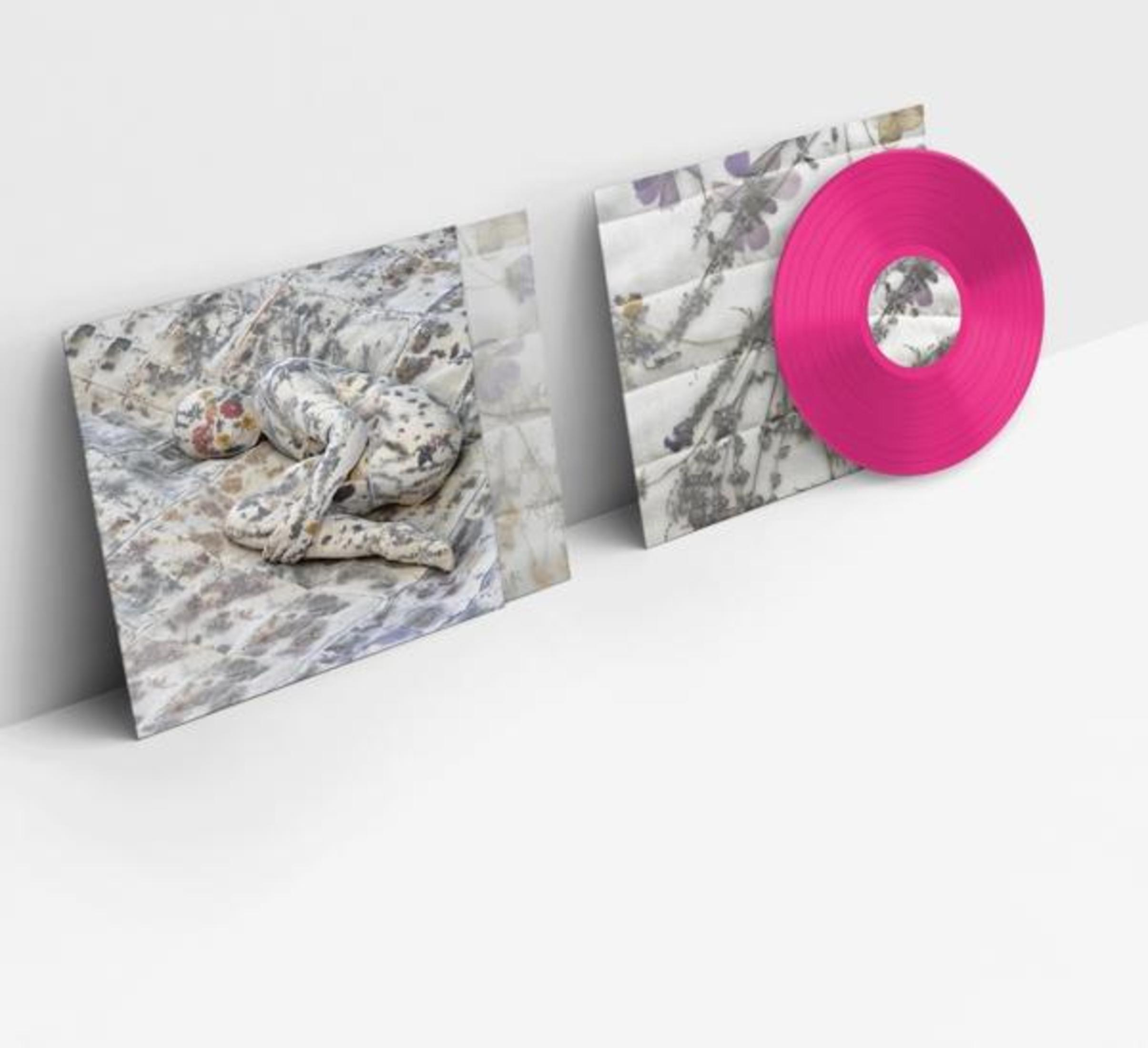 Un disco in vinile rosa giace accanto a una copertina floreale.