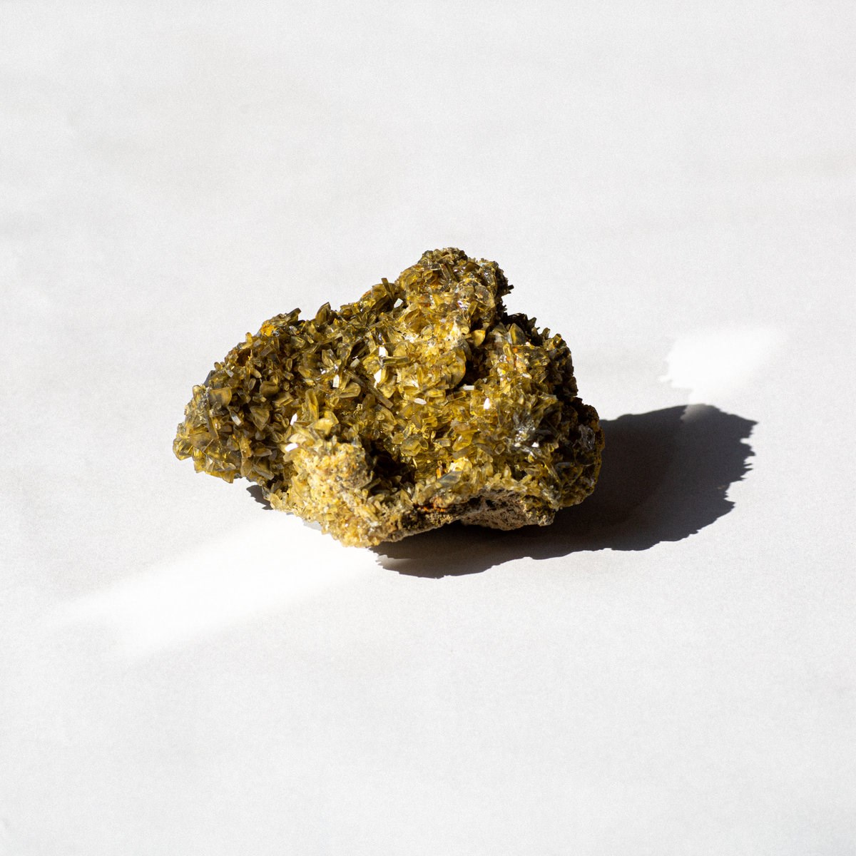 Un grappolo di cristalli giallo dorato su sfondo bianco.