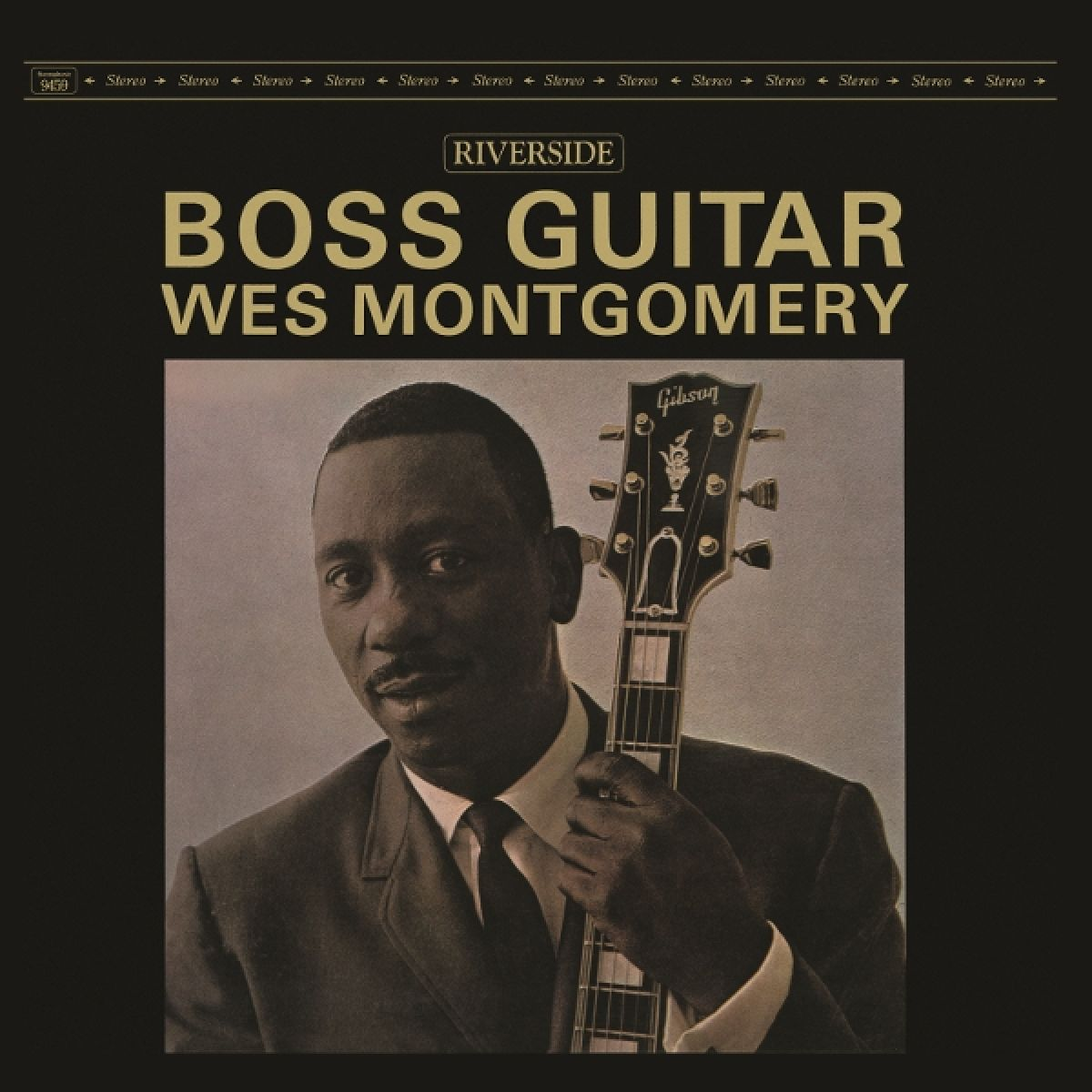 Uomo in giacca e cravatta tiene una chitarra, "Boss Guitar Wes Montgomery".