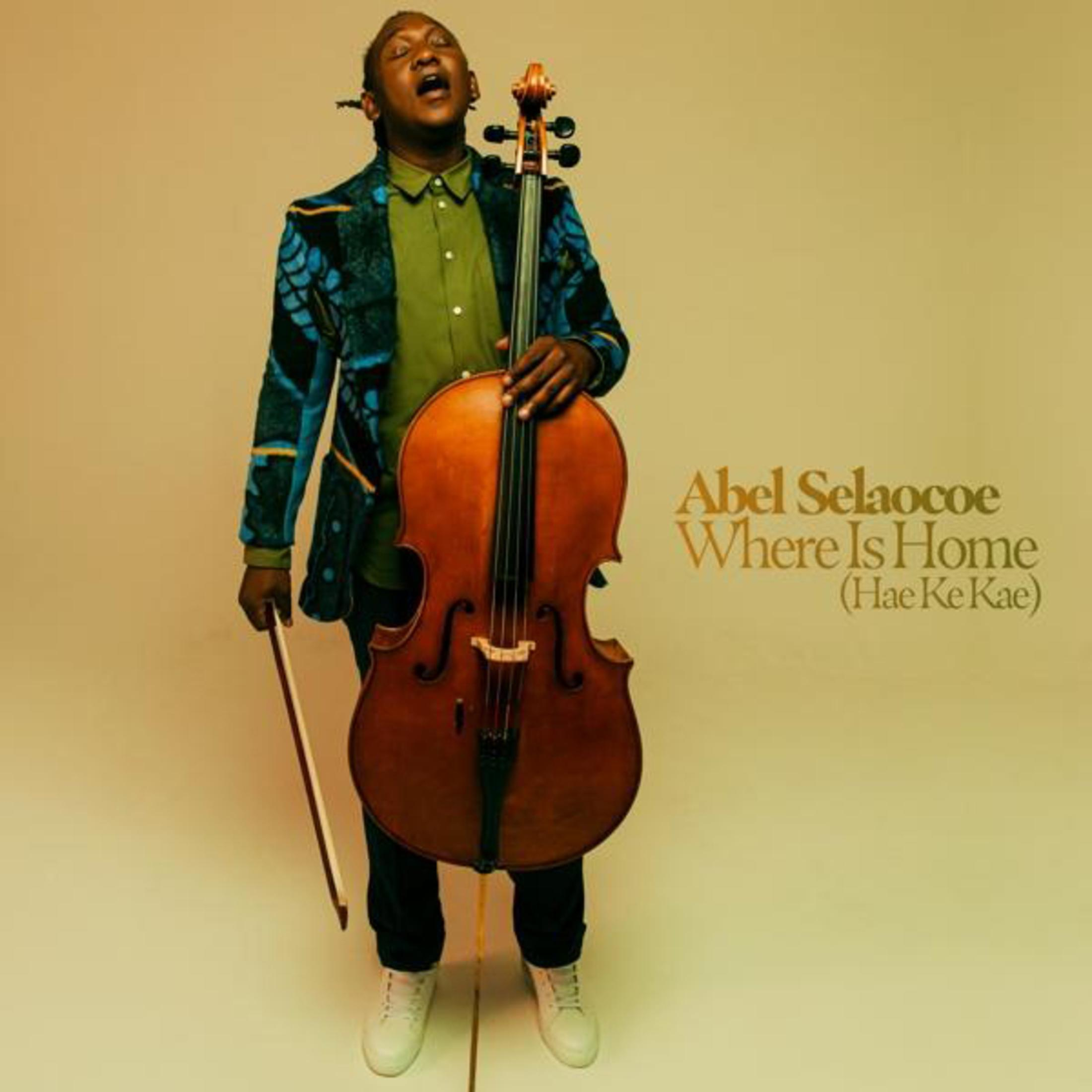 Un uomo con violoncello e archetto, indossa una giacca colorata.