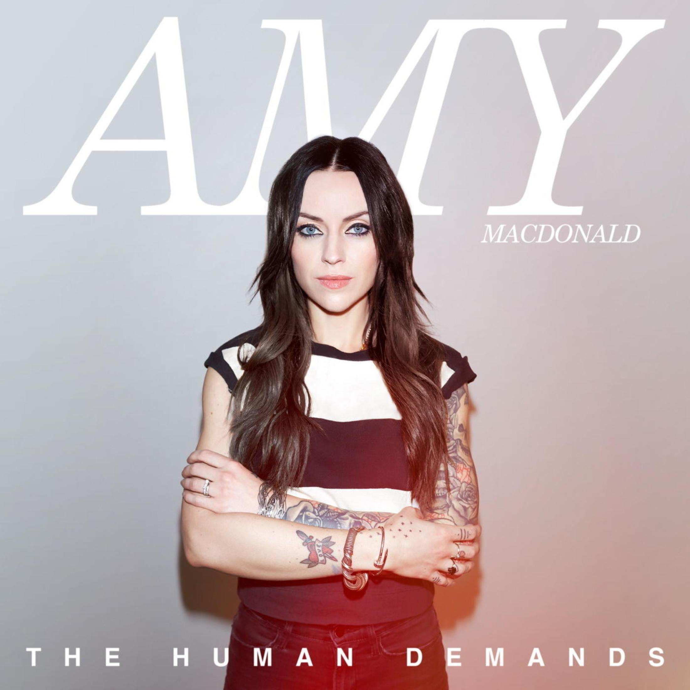 Amy MacDonald con braccia tatuate e top a righe.