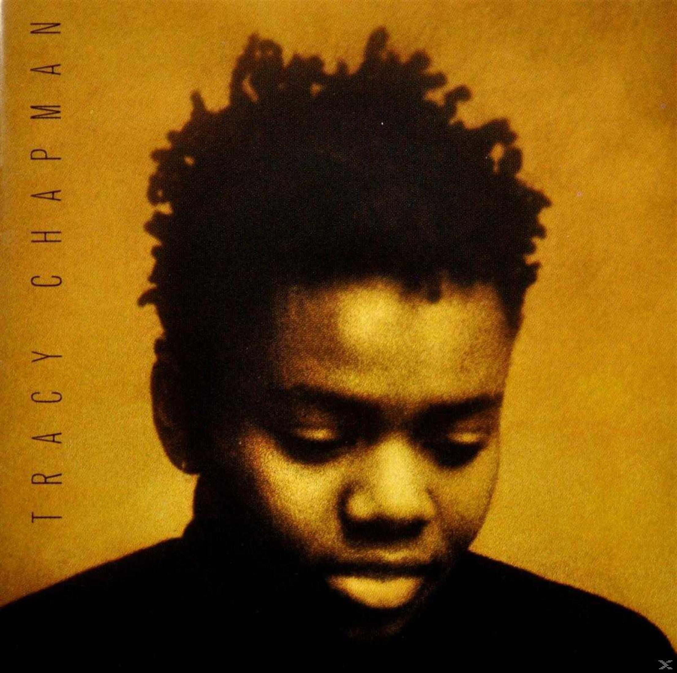 Ritratto di Tracy Chapman con capelli scuri su sfondo giallo.