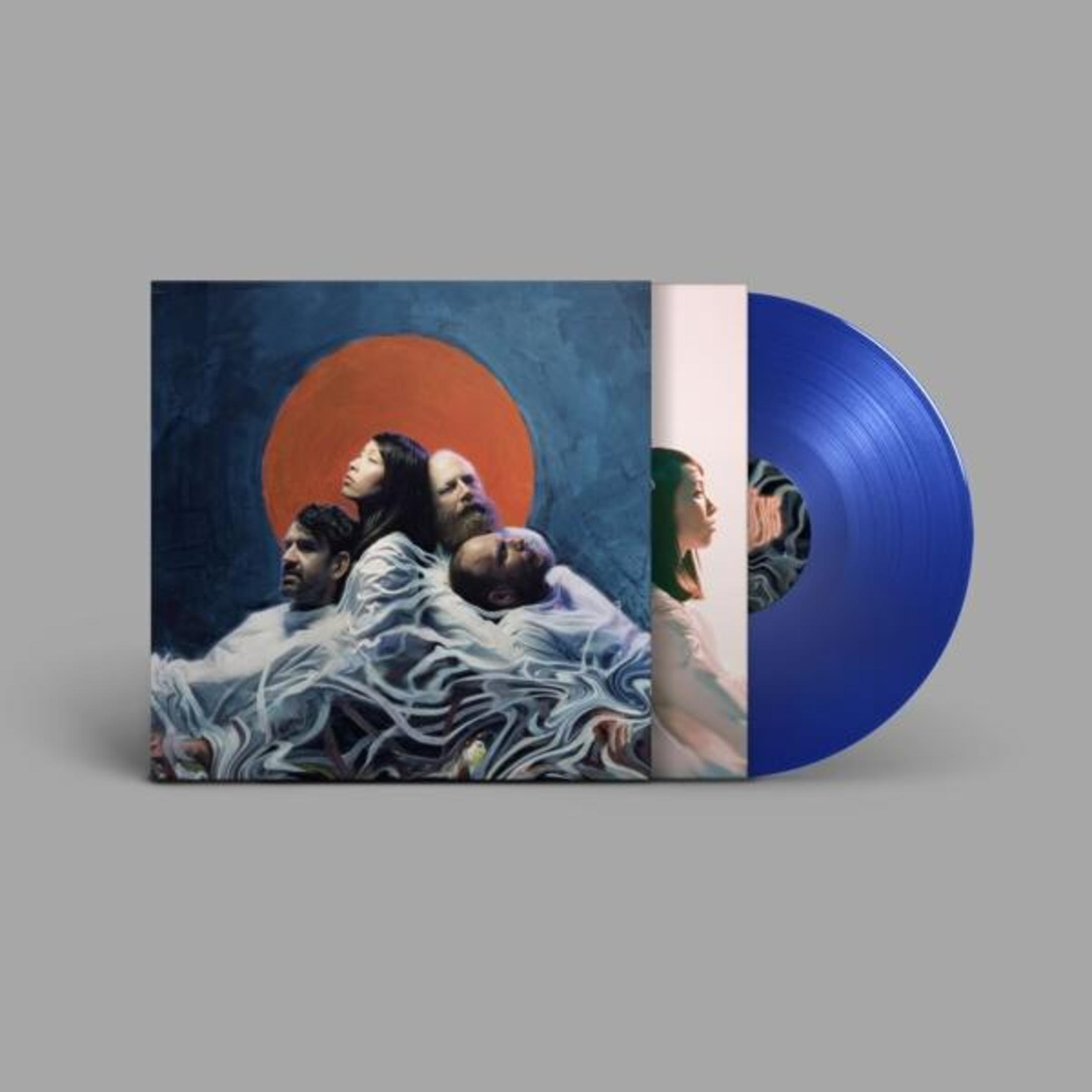 Copertina disco mostra quattro persone davanti a cerchio arancio su blu. Un disco vinile blu accanto.