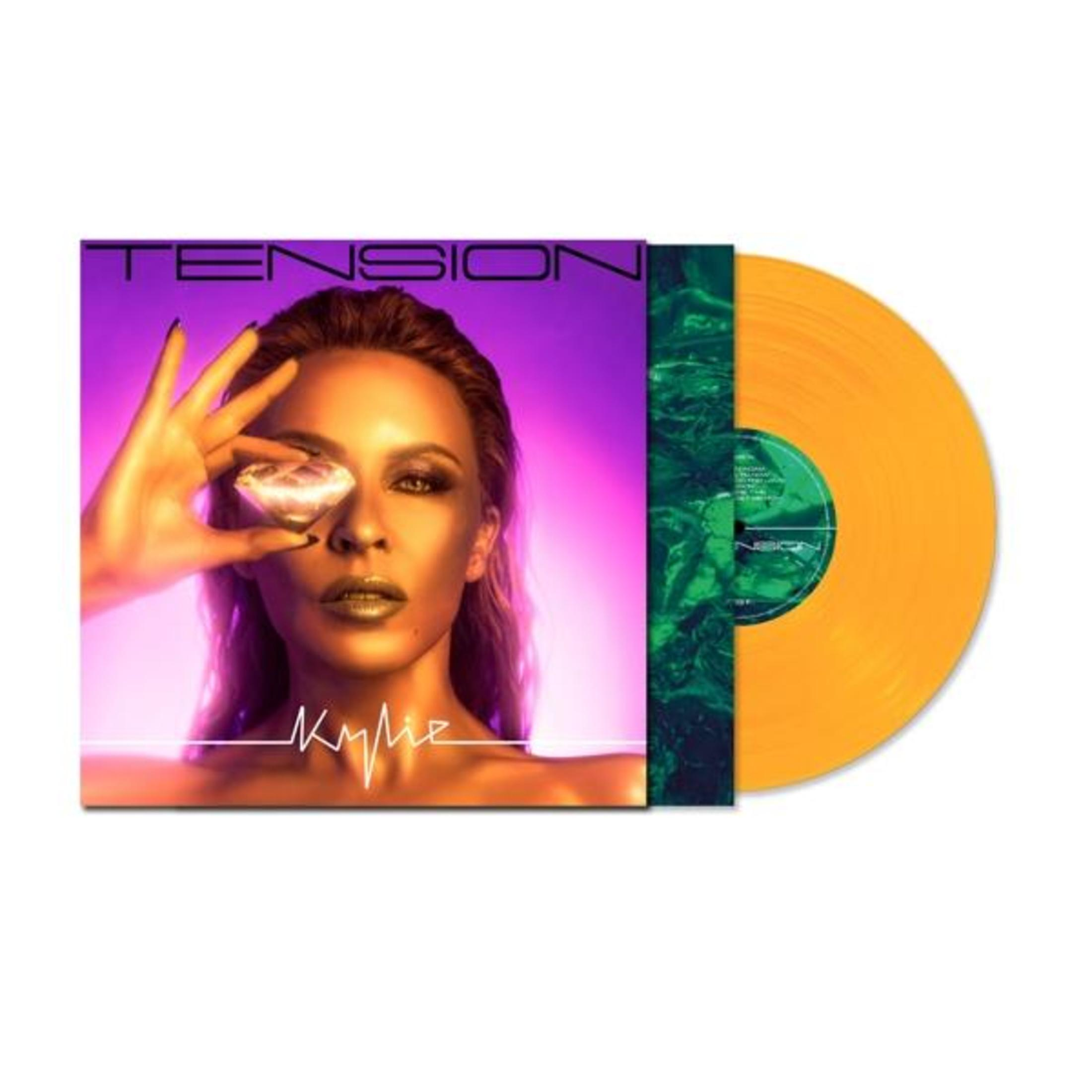 Kylie Minogue con diamante sull'occhio accanto a un disco in vinile arancione.