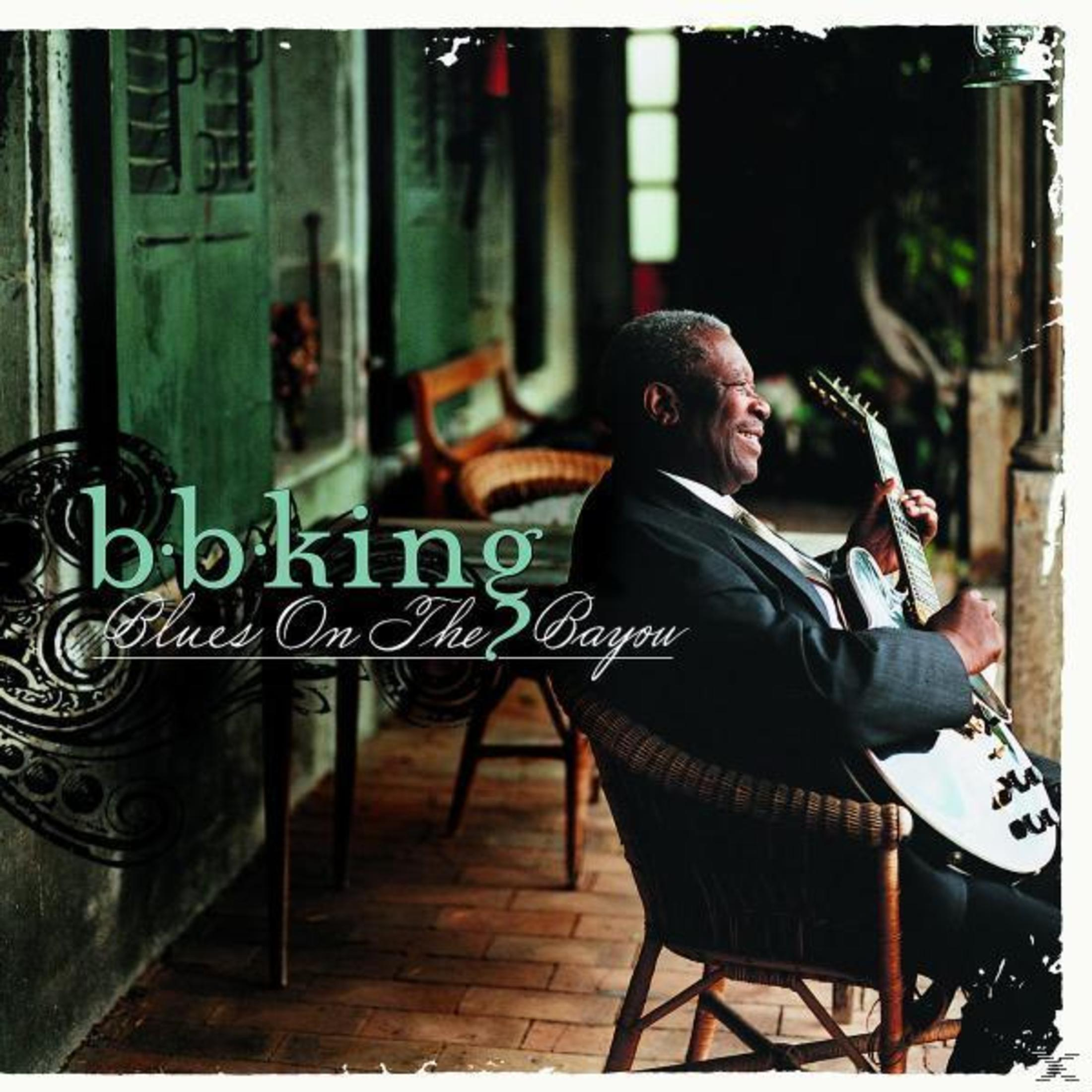 B.B. King è seduto su una sedia di vimini e suona la chitarra su un portico.