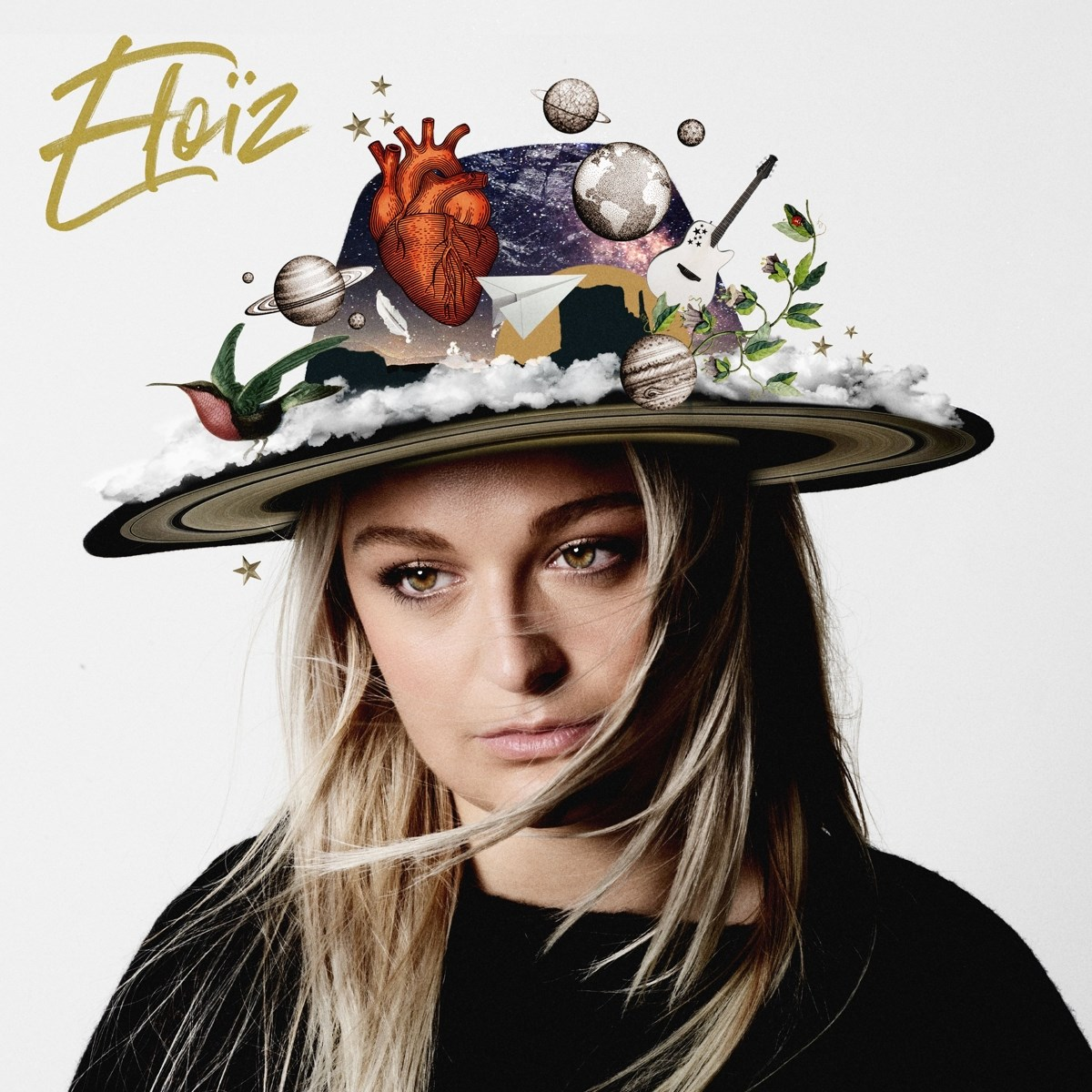 Una donna con un cappello adornato con oggetti spaziali, un cuore e un colibrì.