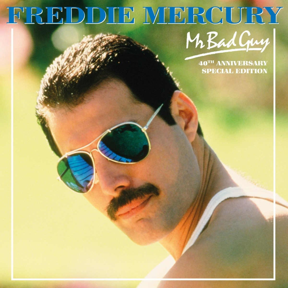 Freddie Mercury indossa occhiali da sole e una canotta bianca, con testo sullo sfondo.