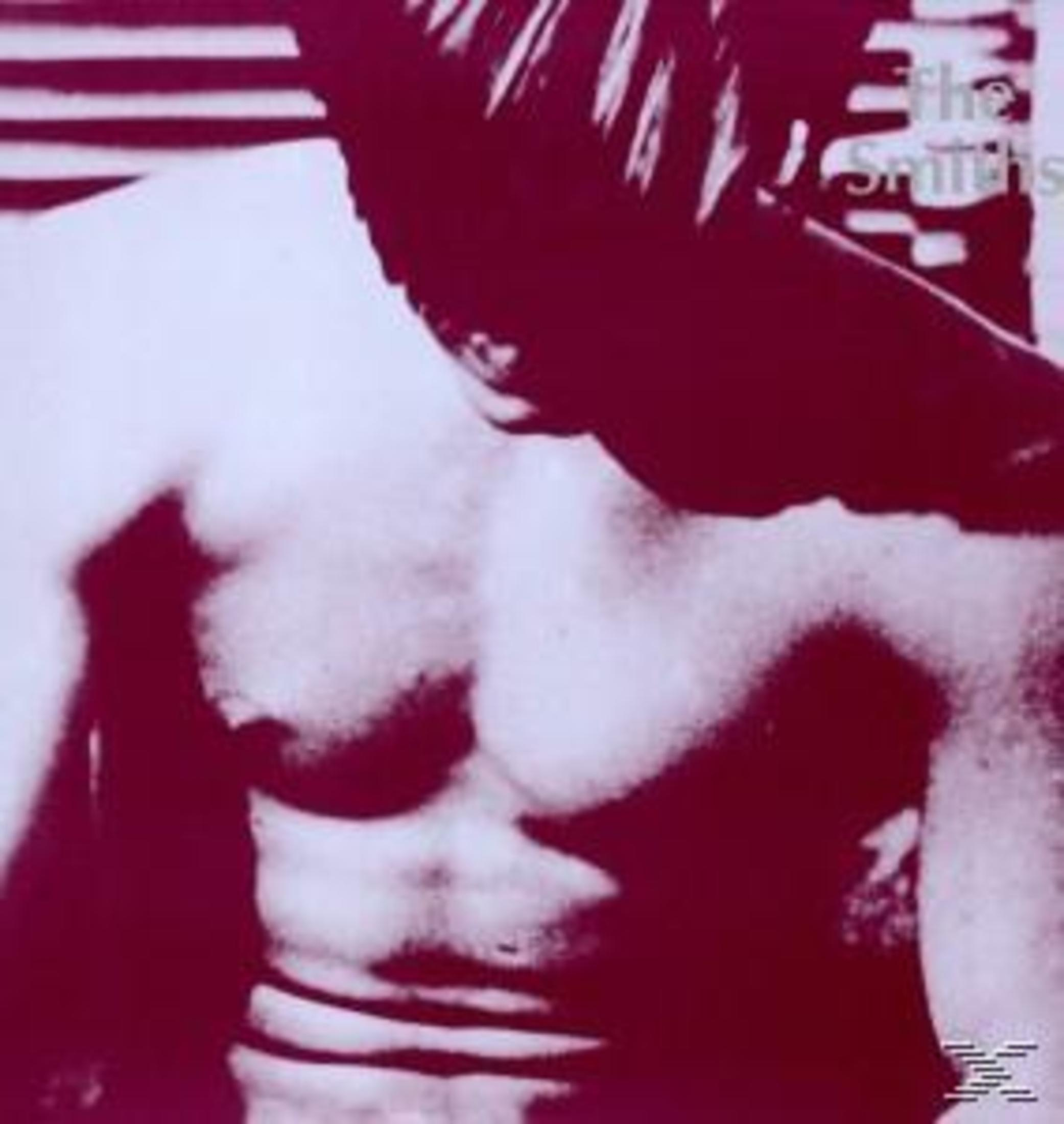 Un uomo a torso nudo in rosso scuro e bianco. L'uomo è chino in avanti.