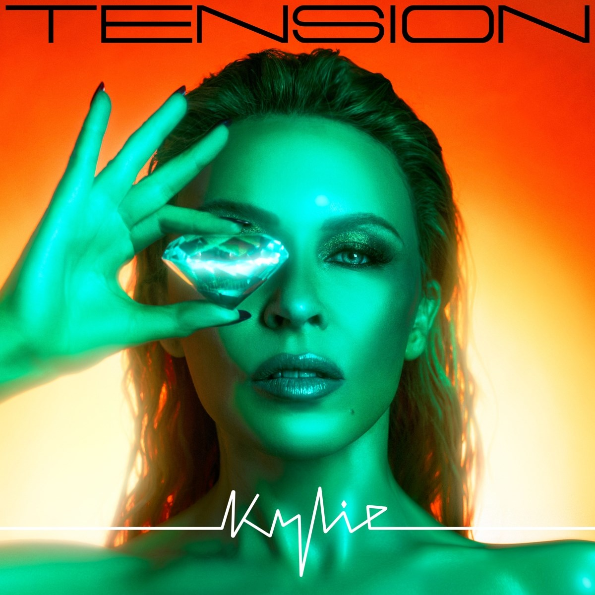 Donna tiene un diamante sull'occhio, illuminazione verde e arancione, testo TENSION e Kylie.
