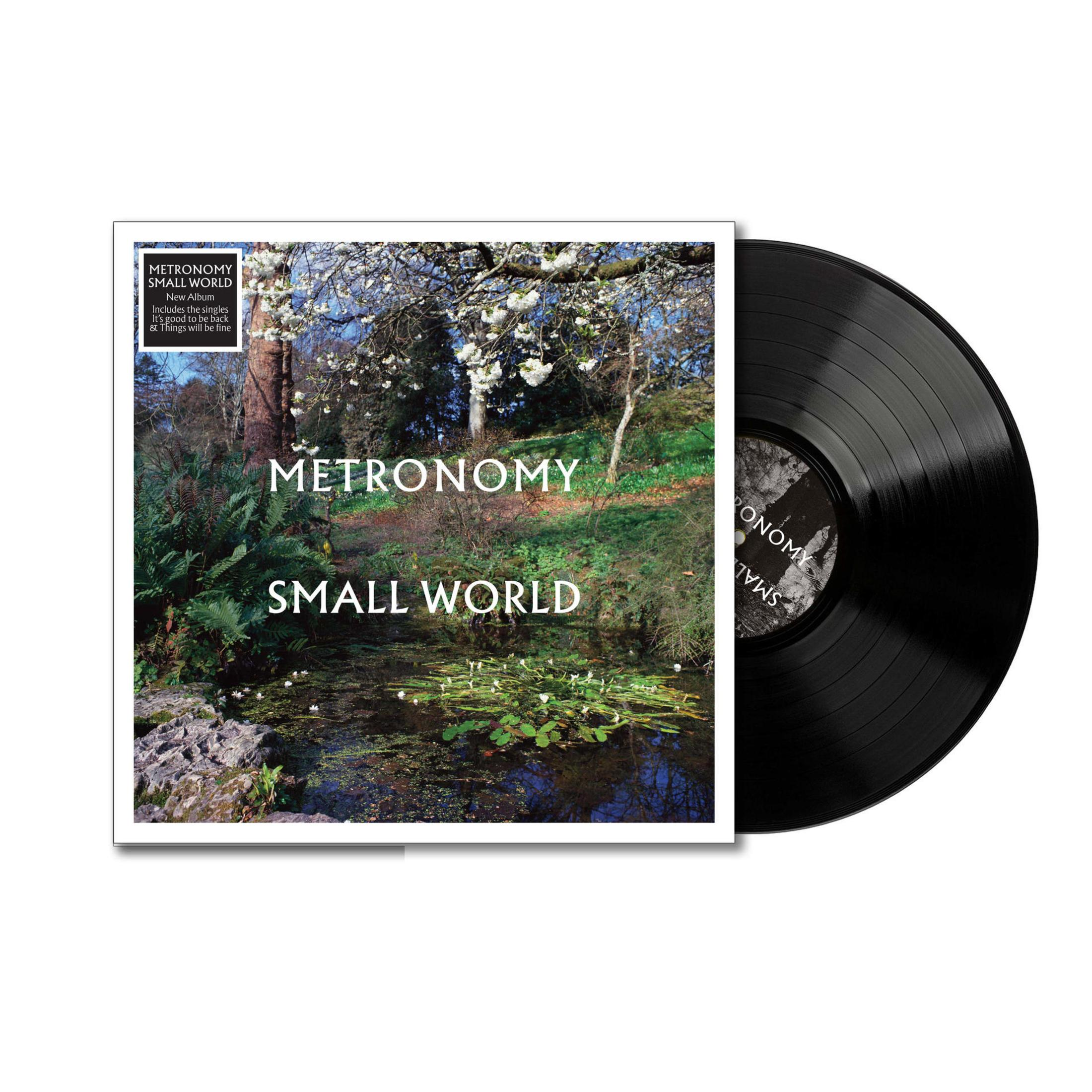 Disco in vinile accanto alla copertina dell'album con scena di bosco e stagno. Metronomy Small World.