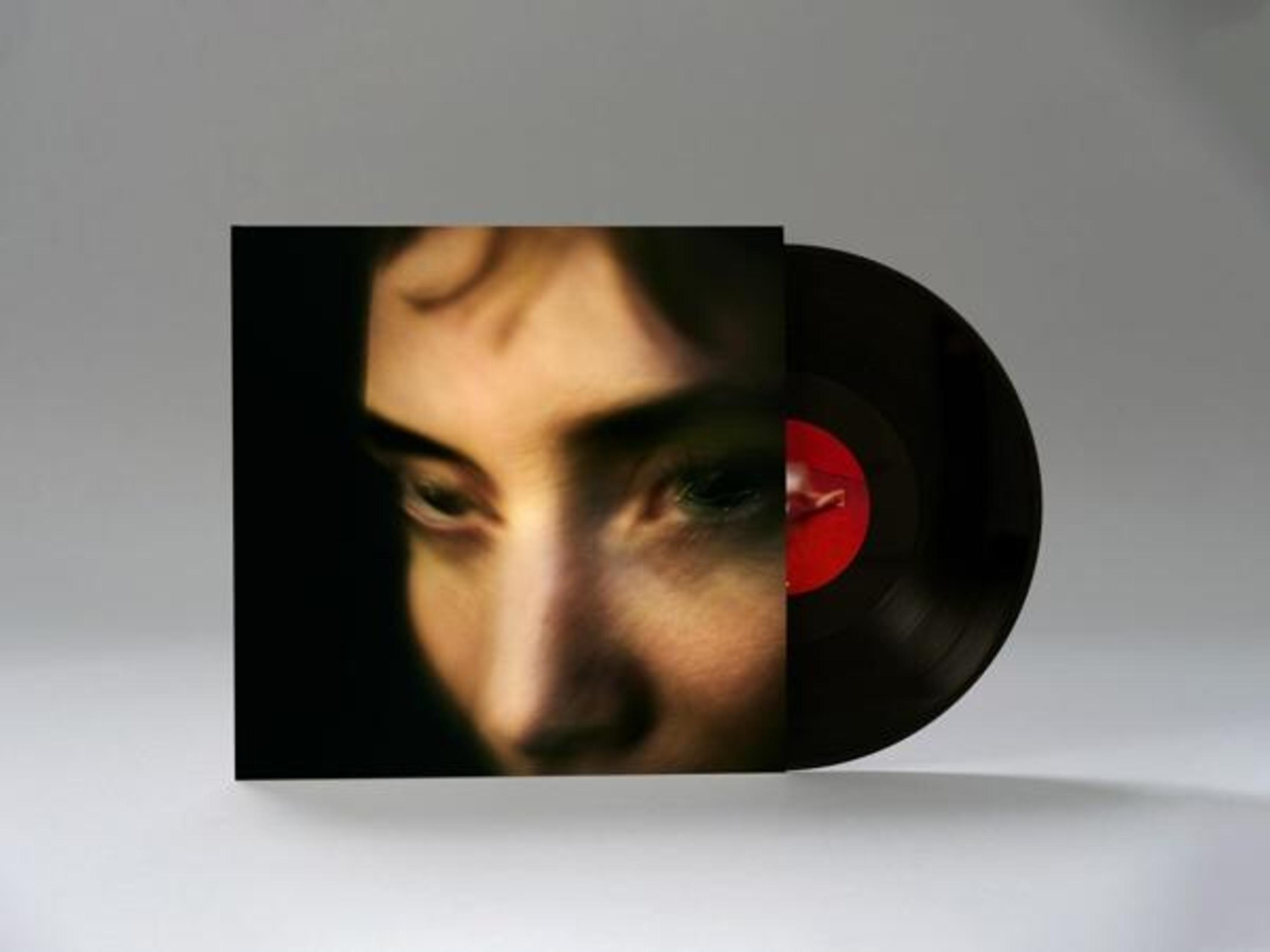 Primo piano di un volto accanto a un disco in vinile.