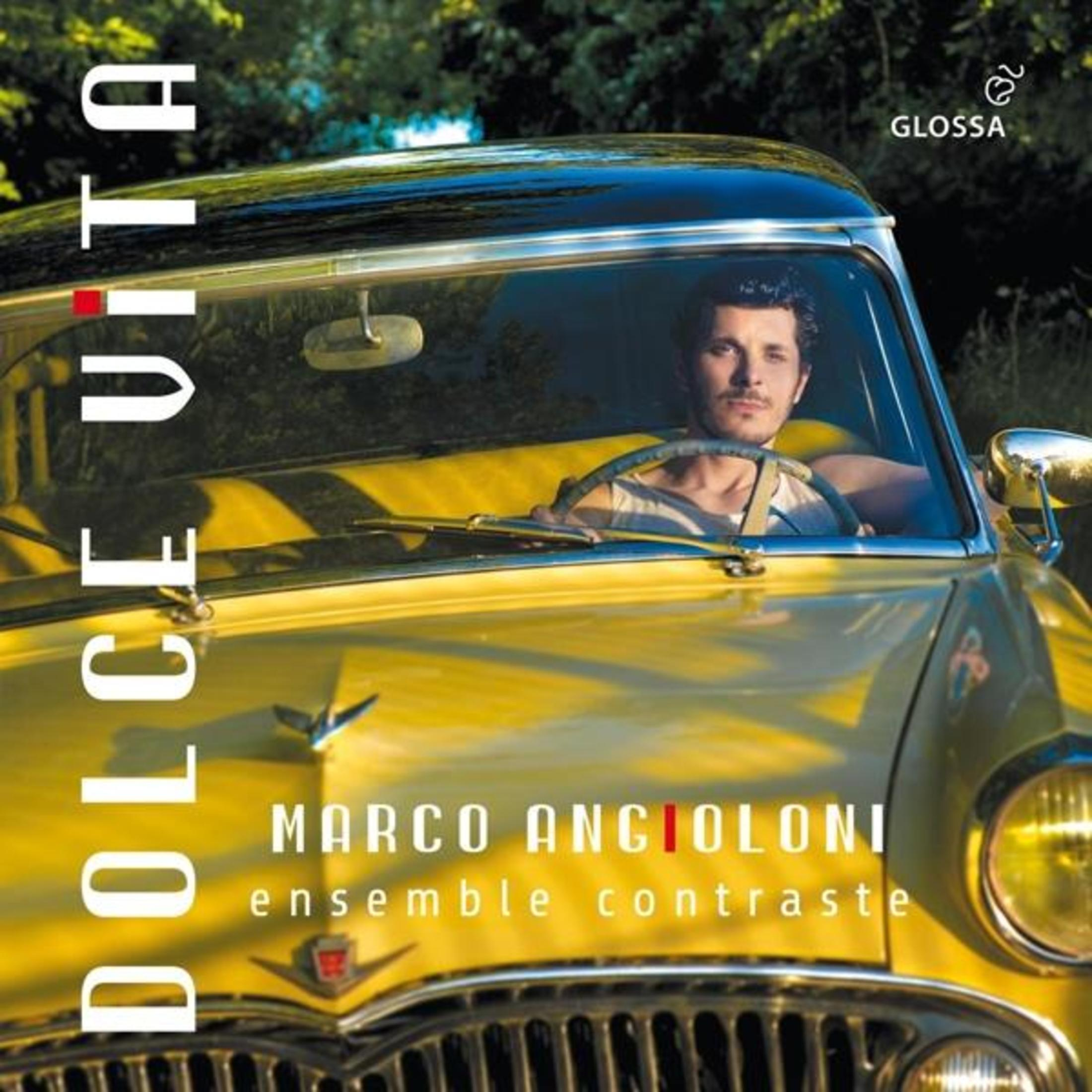 Uomo alla guida di un'auto gialla d'epoca. "DOLCE VITA" e nome.