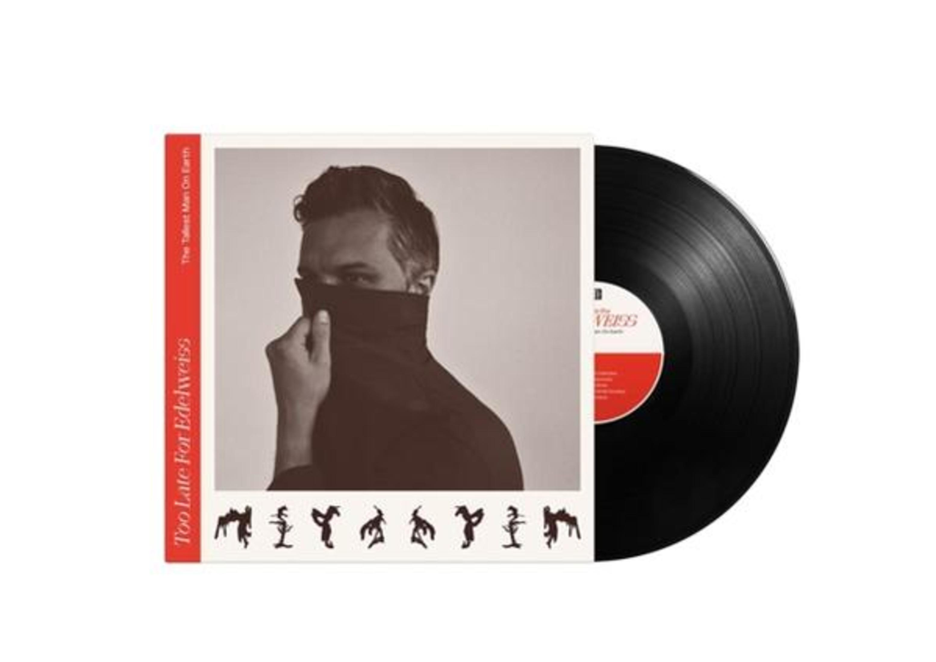 Un uomo con dolcevita nero che si copre il viso accanto a un disco in vinile.