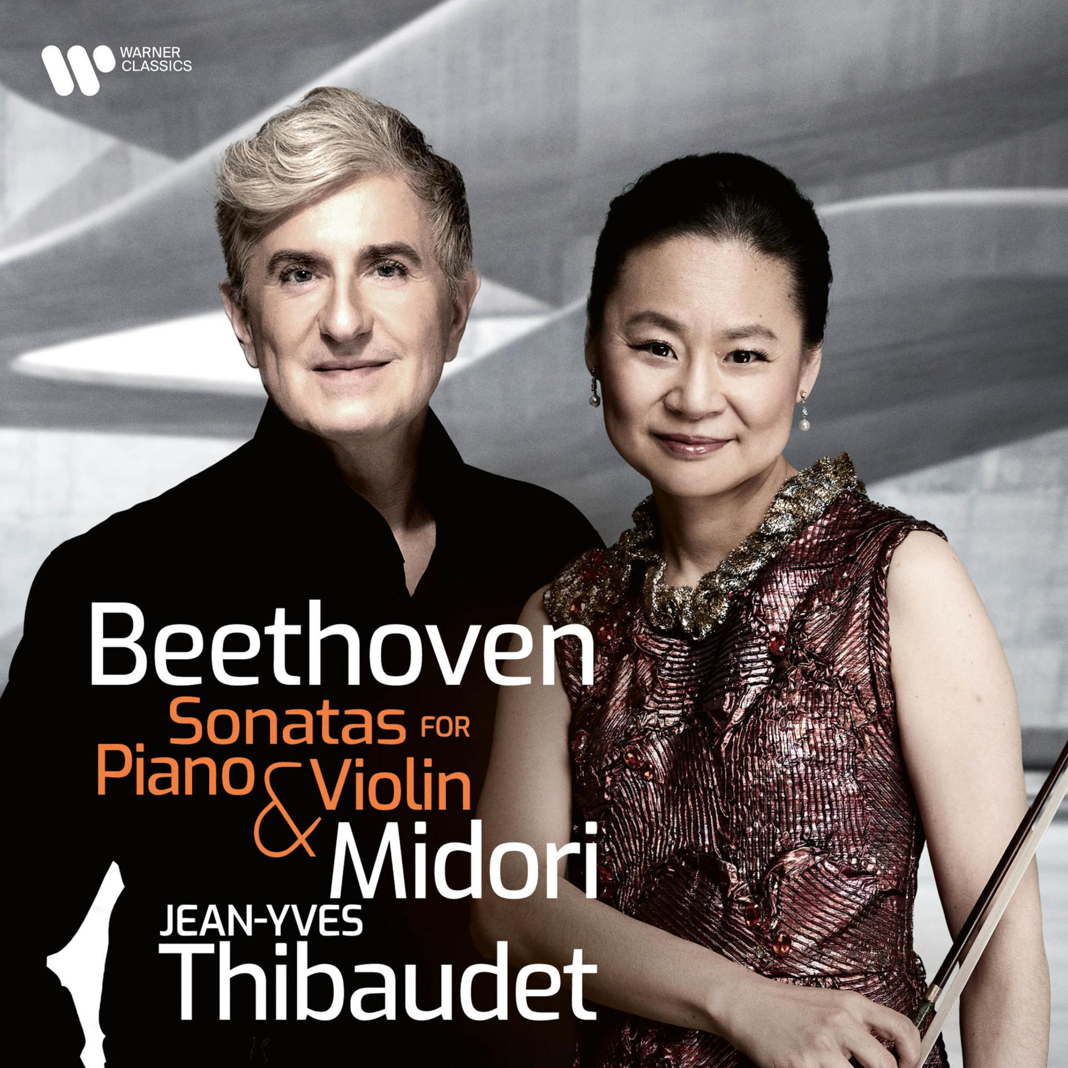 Un uomo e una donna posano su uno sfondo grigio. Il testo menziona le Sonate di Beethoven.