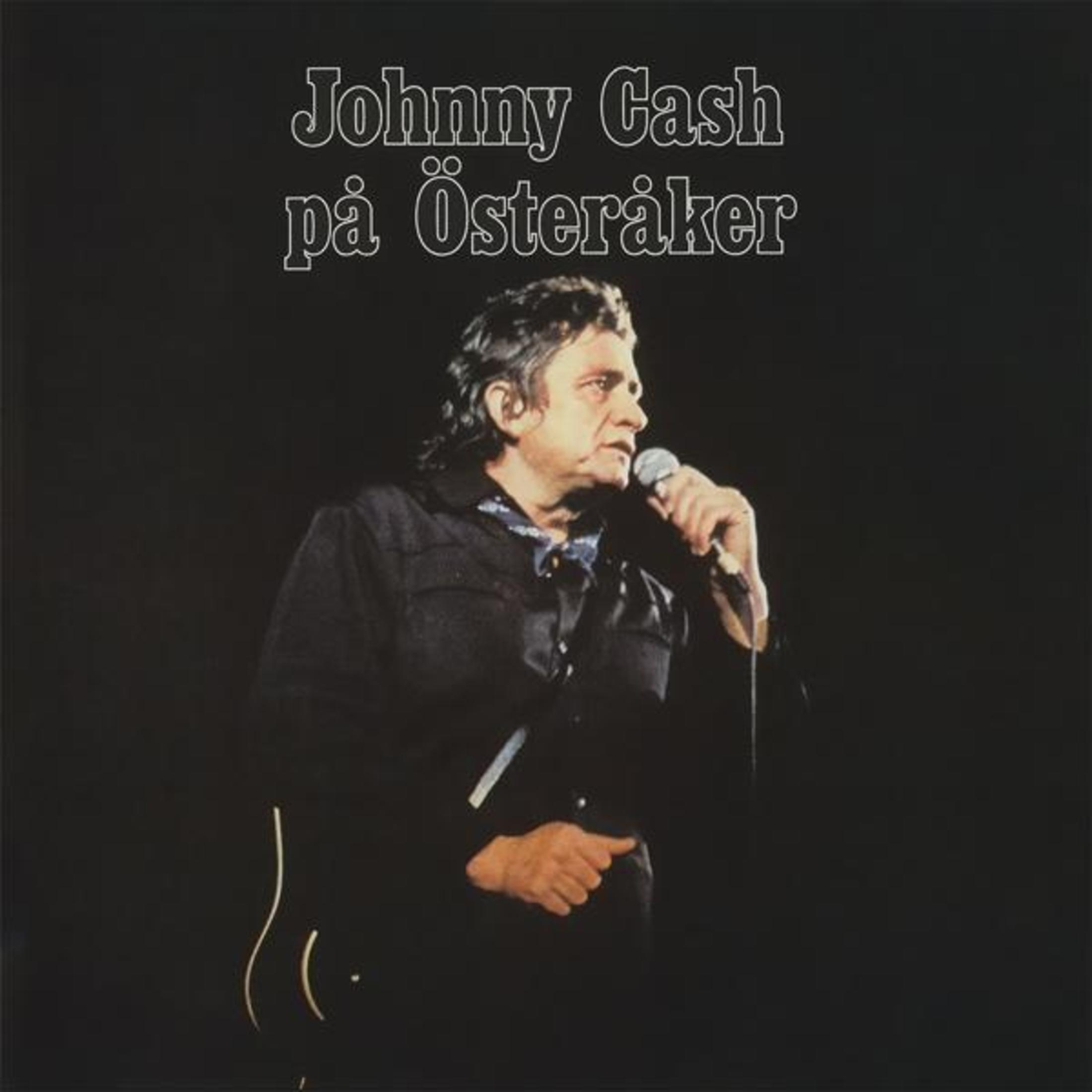 Johnny Cash zingt in een microfoon tegen een zwarte achtergrond.
