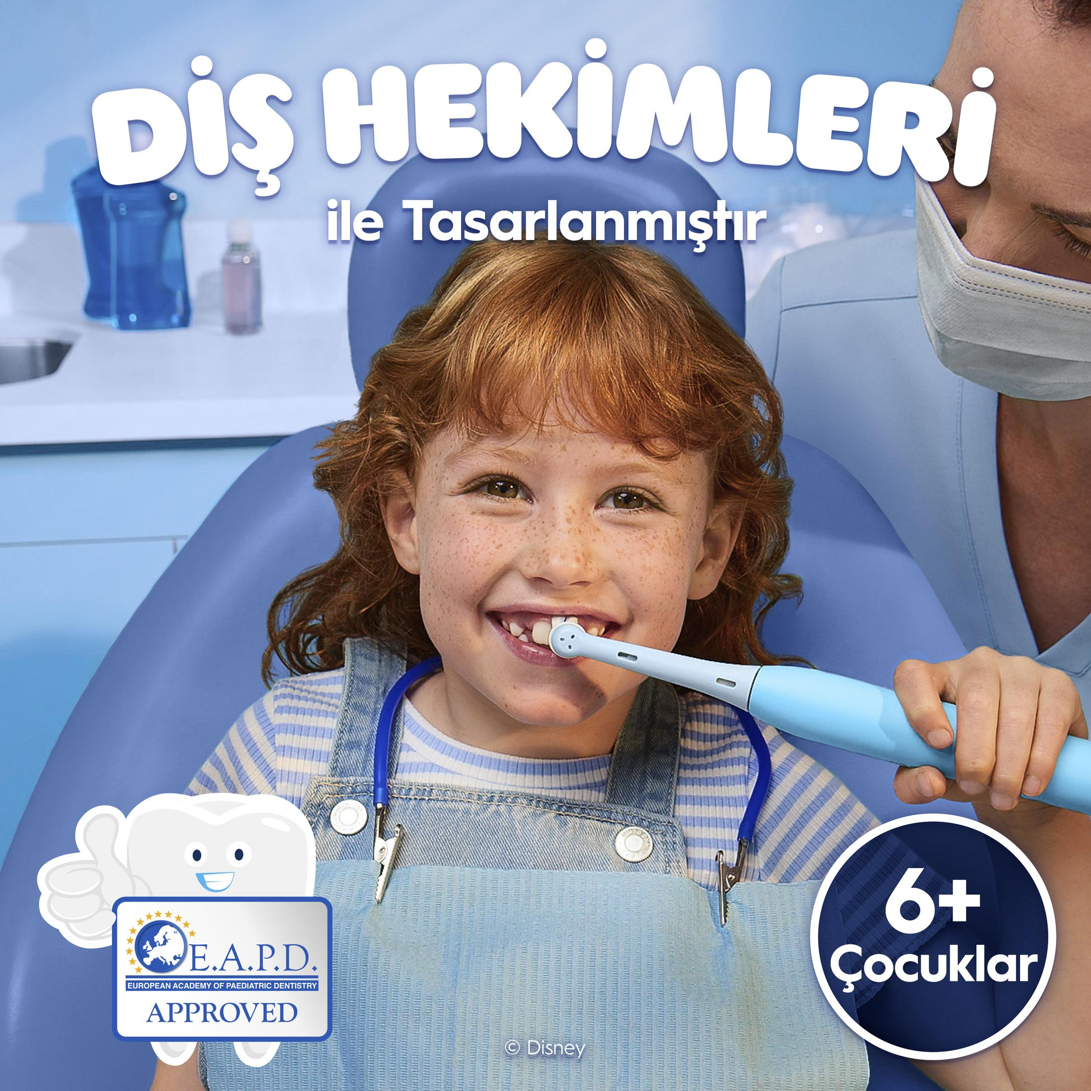 Una bambina dai capelli rossi usa uno spazzolino elettrico su una poltrona dentale.
