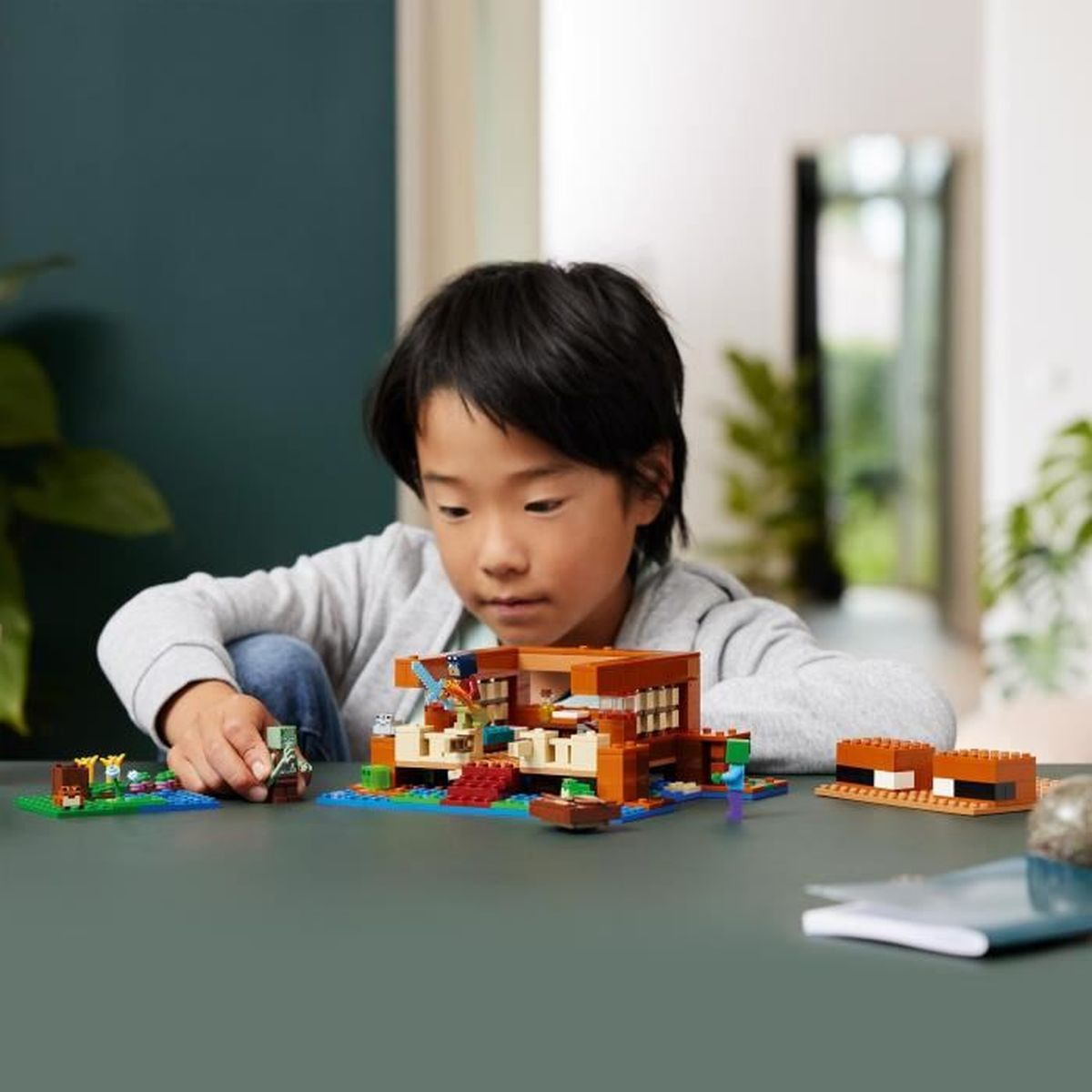 Un ragazzo costruisce una casa LEGO di Minecraft con figure e accessori.