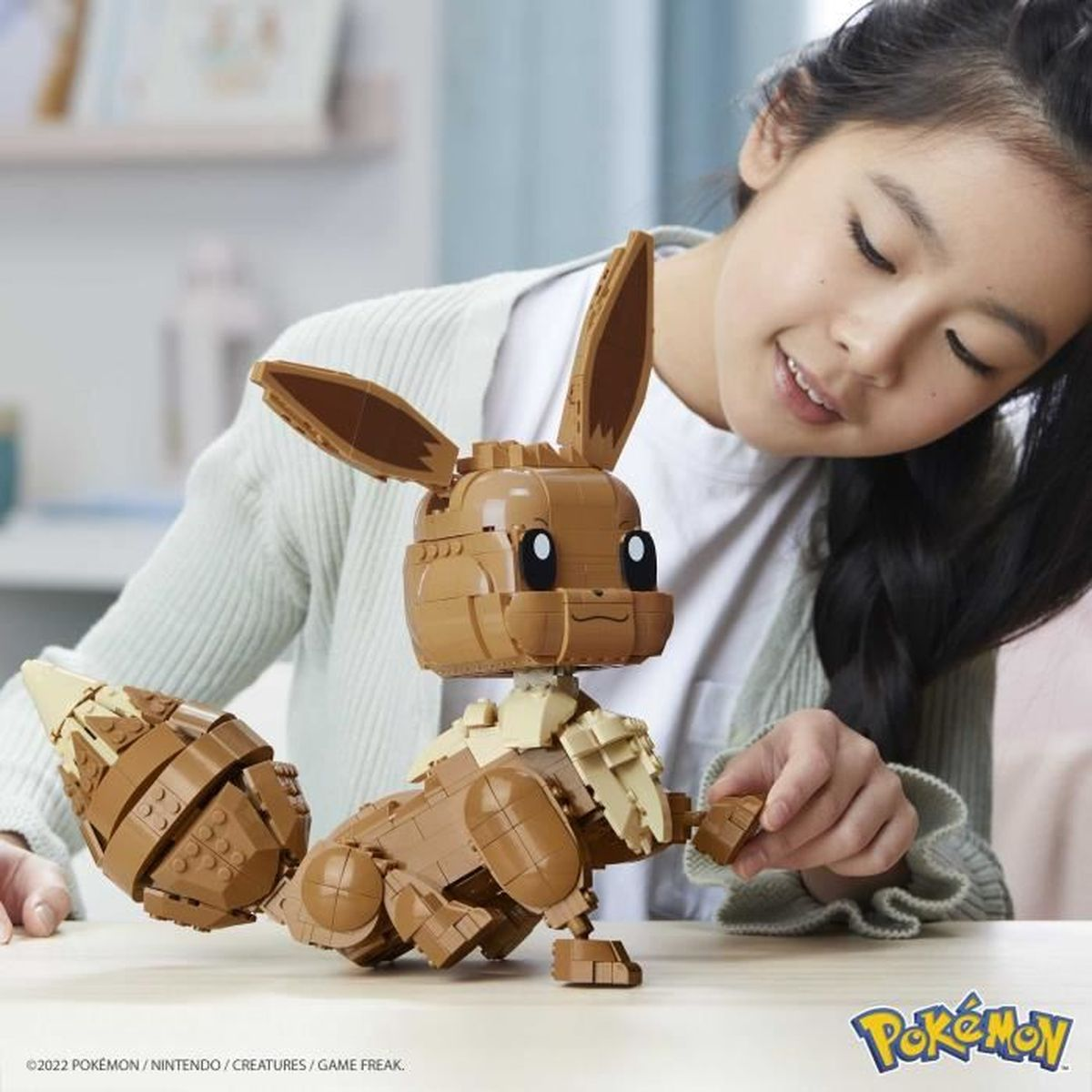 Ein Mädchen baut einen braunen Lego-Eevee mit langen Ohren und buschigem Schwanz.