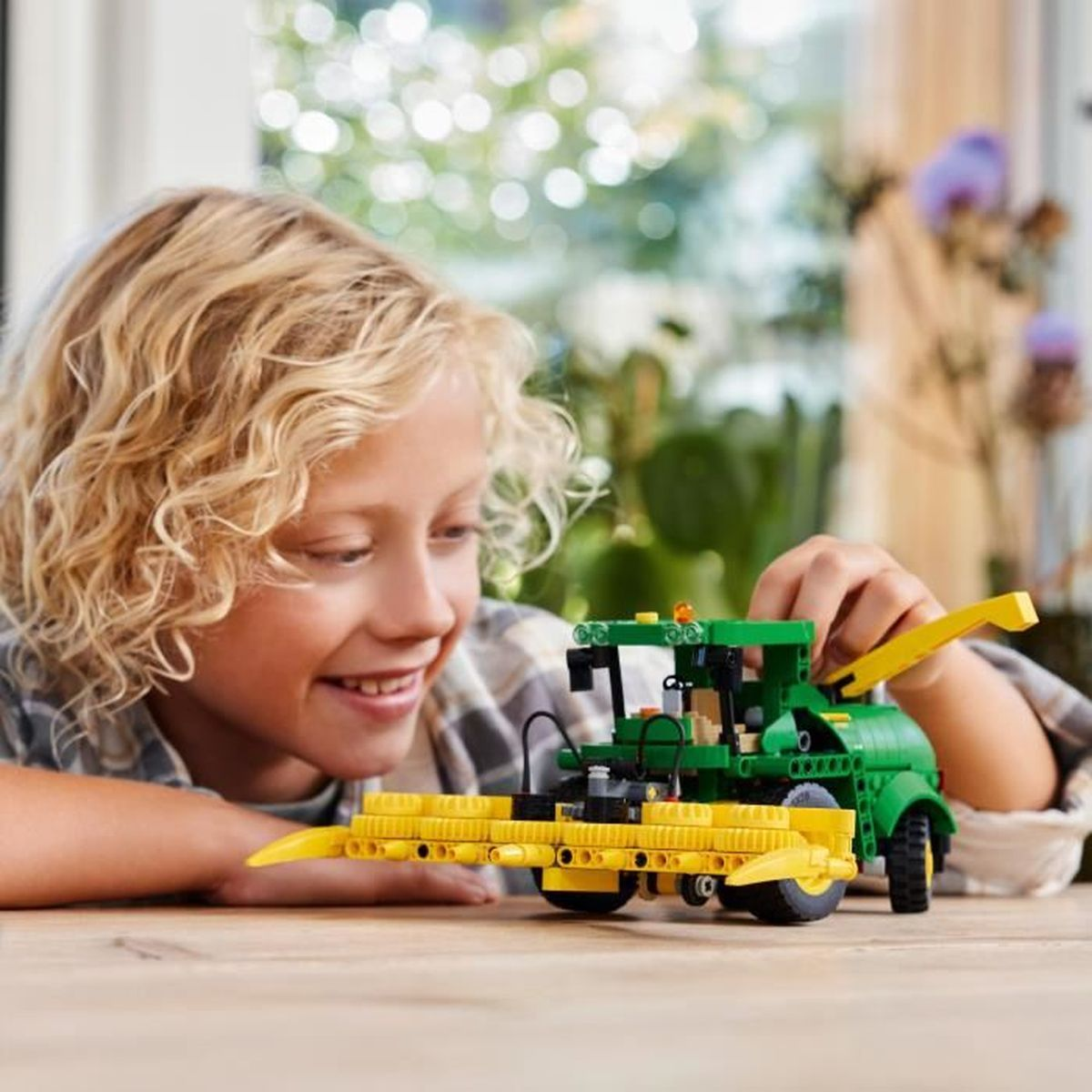Ein Junge baut einen grünen und gelben Spielzeug-Traktor mit detaillierten Elementen.