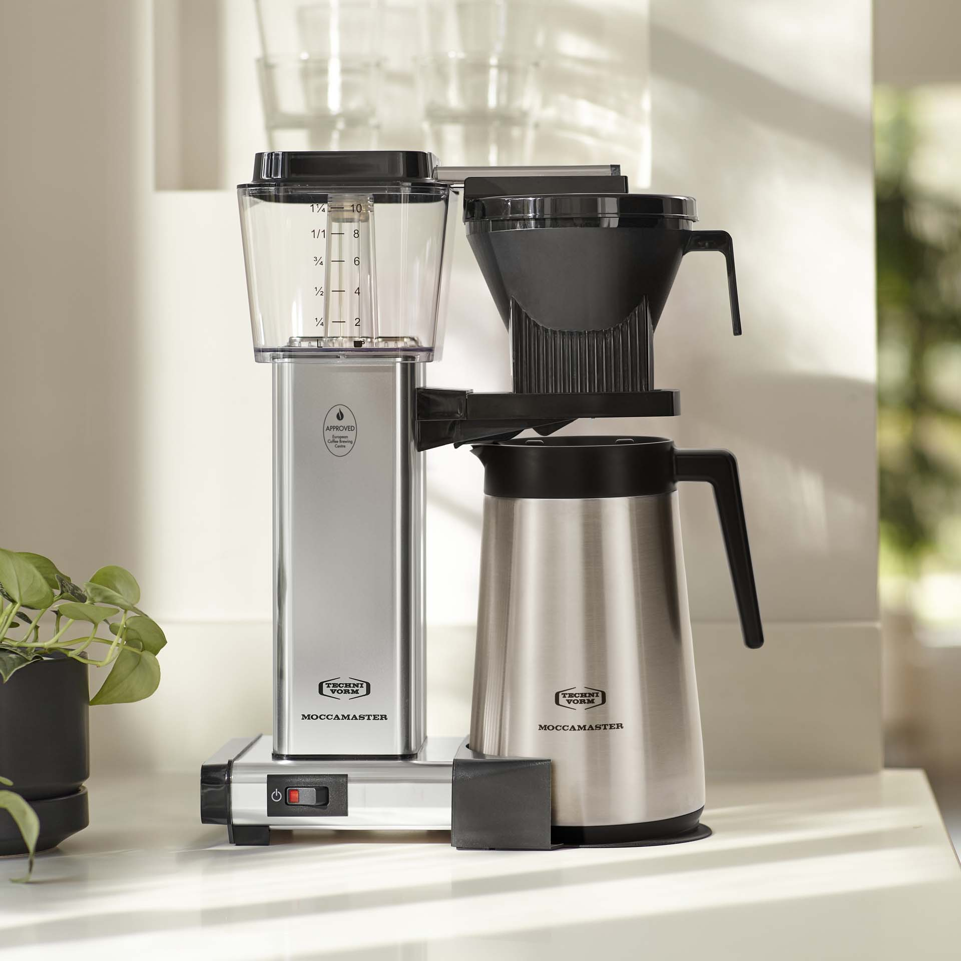 Une cafetière argentée avec porte-filtre noir et une carafe isotherme.