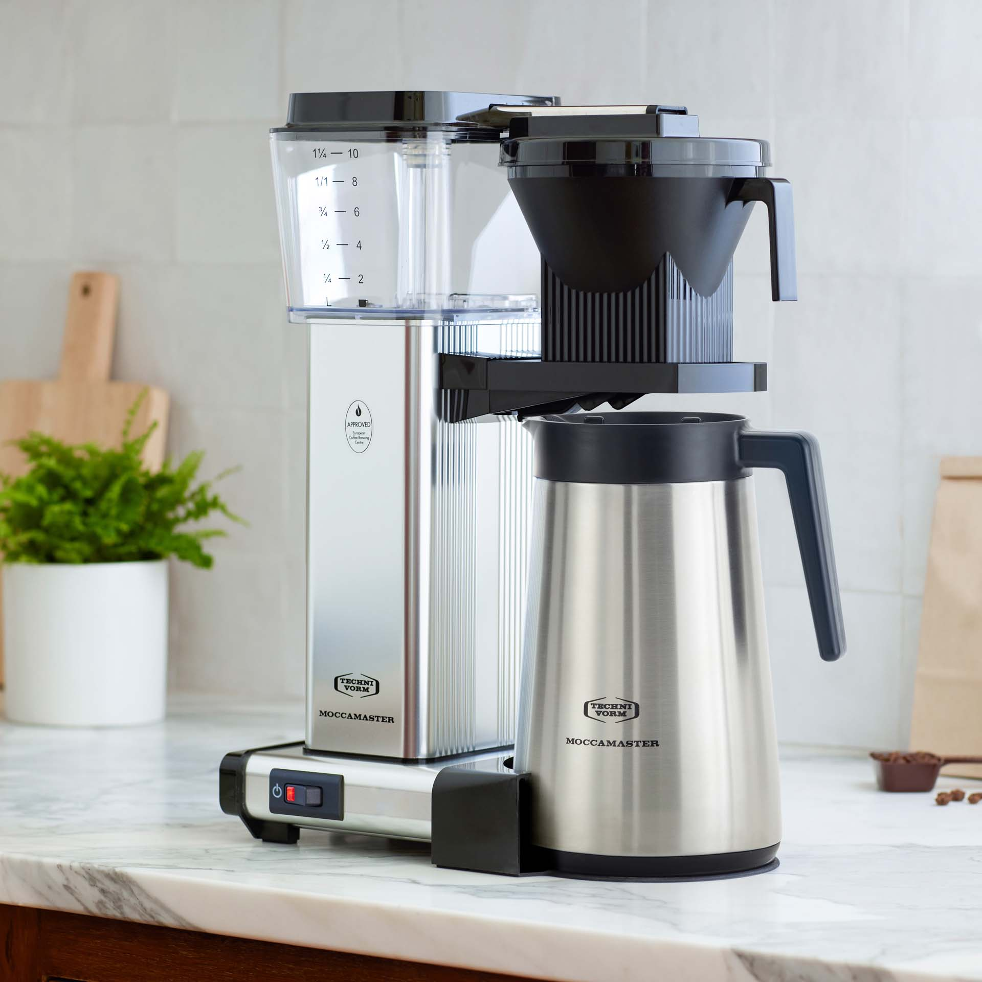Cafetière Moccamaster argentée avec carafe isotherme noire et verseuse.