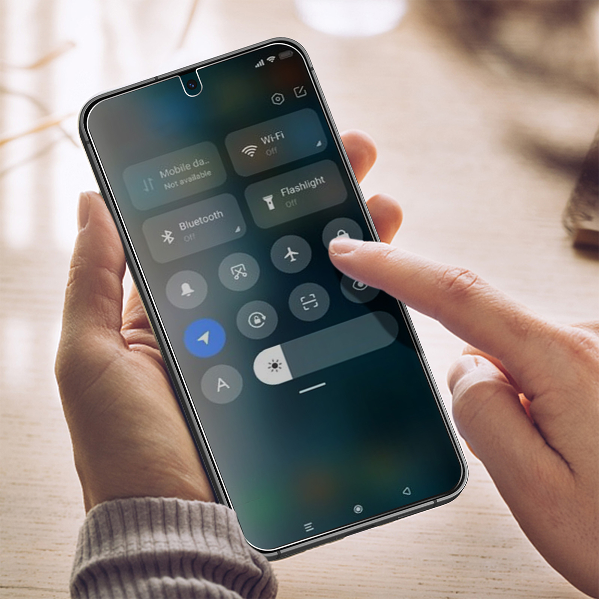 Een vinger drukt op een sloticoon op een smartphone-scherm met snelle instellingen.