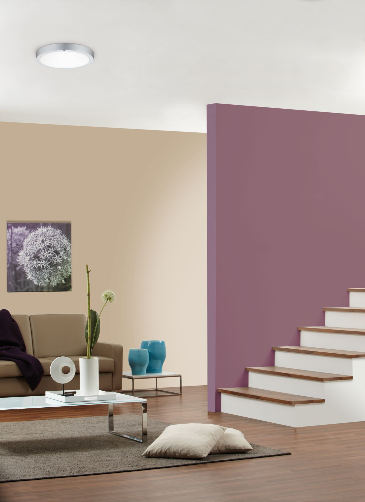 Salon z brązową sofą, stolikiem kawowym, schodami i fioletową ścianą.