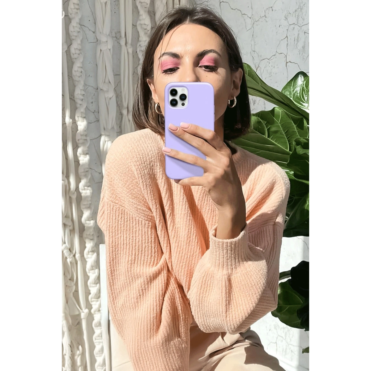 Şeftali kazaklı kadın mor telefonla selfie çekiyor. Pembe göz farı.